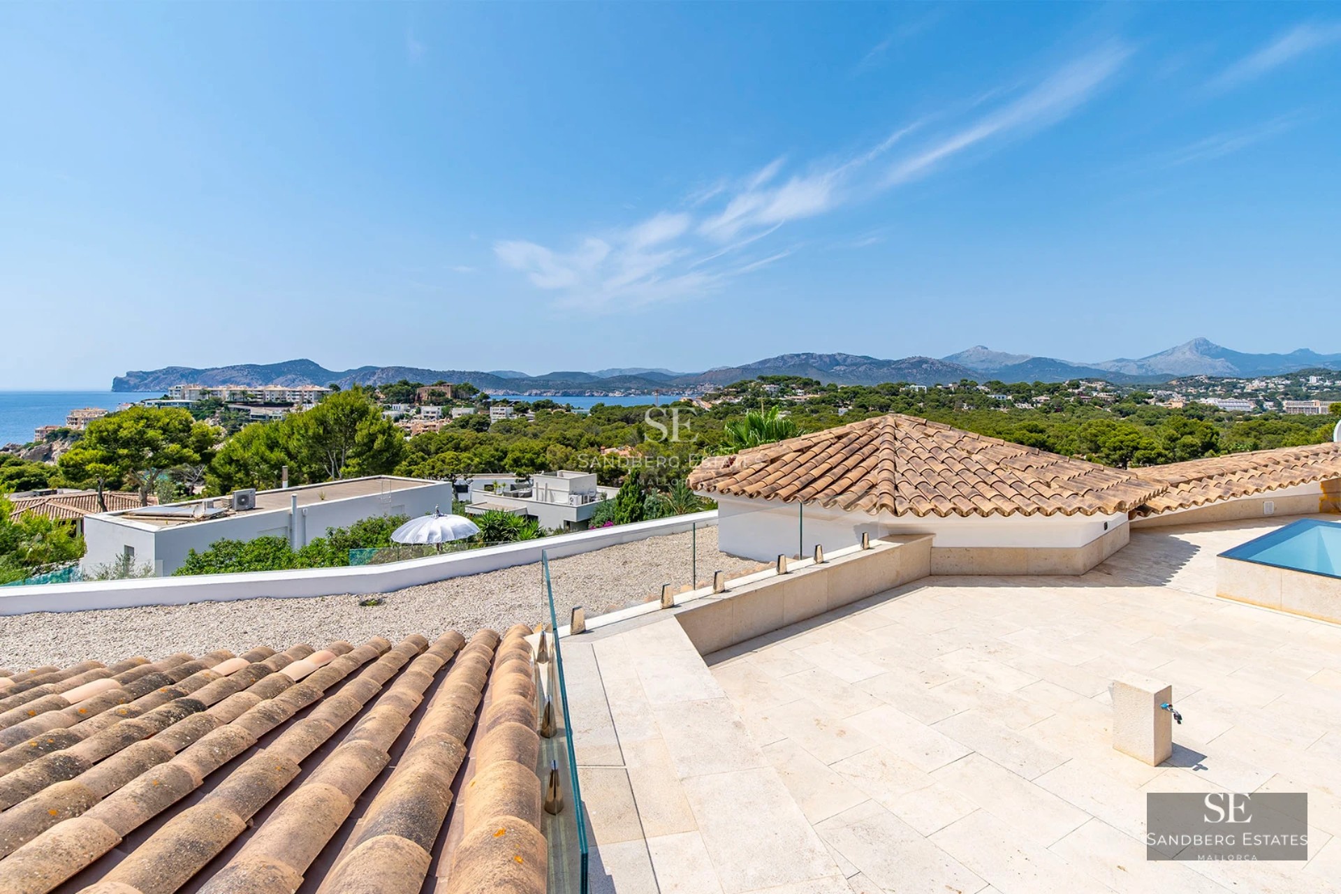 Exterior of a modern villa featuring a pool, large windows, and minimalist design. Lush garden and blue sky.
