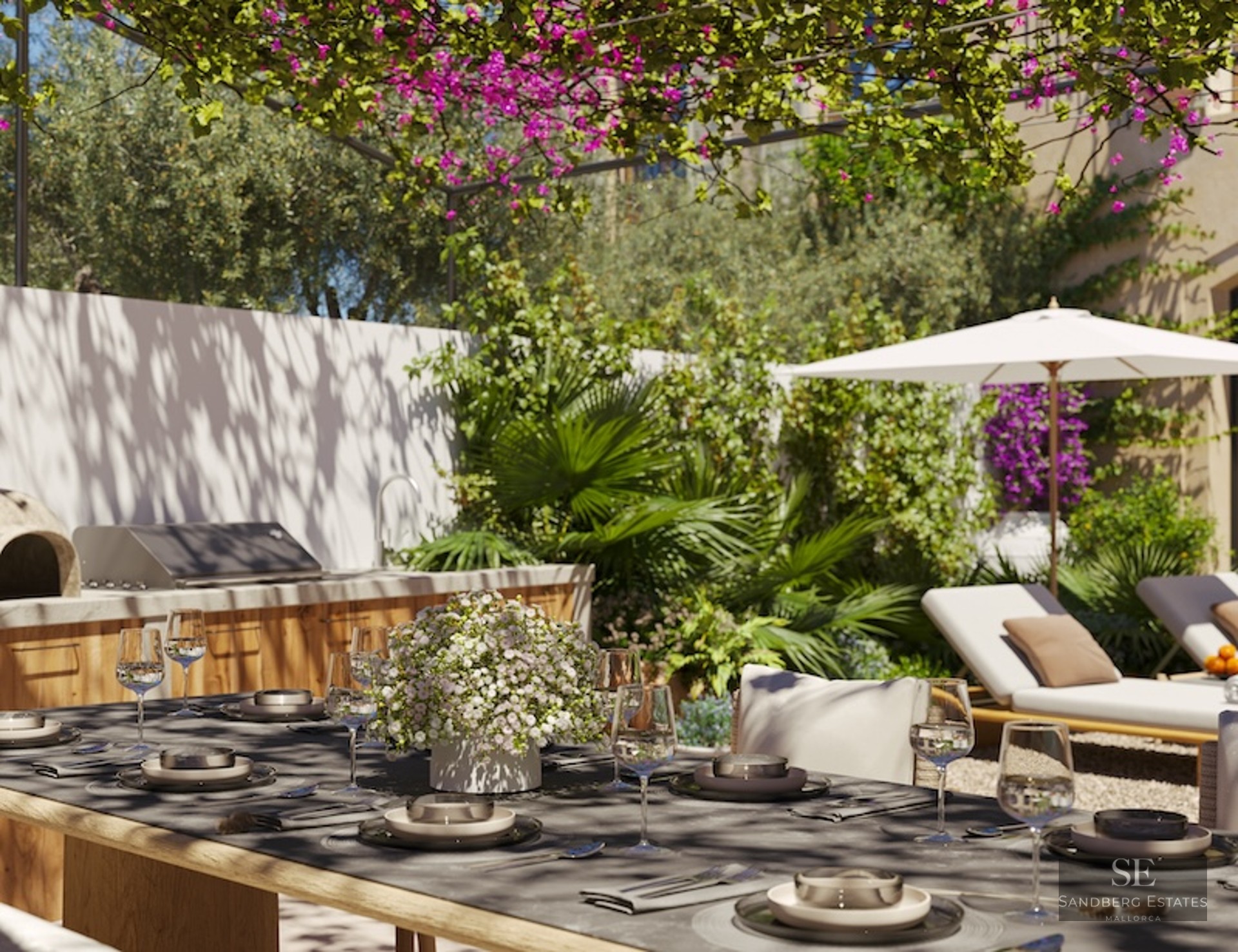 Sun-drenched terrace featuring an outdoor kitchen, dining under a flowered pergola, and loungers with an umbrella.