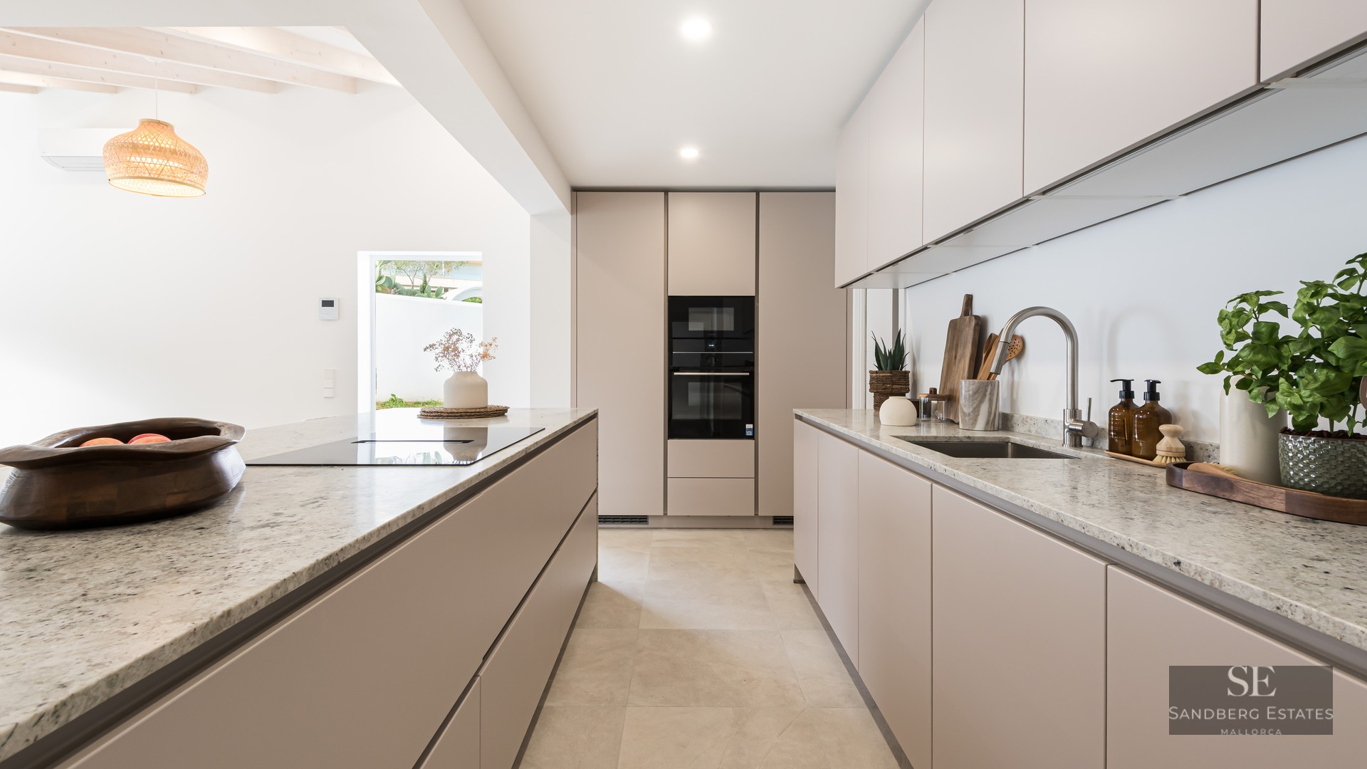 A contemporary beige kitchen featuring granite countertops, a center island, and integrated high-end appliances.