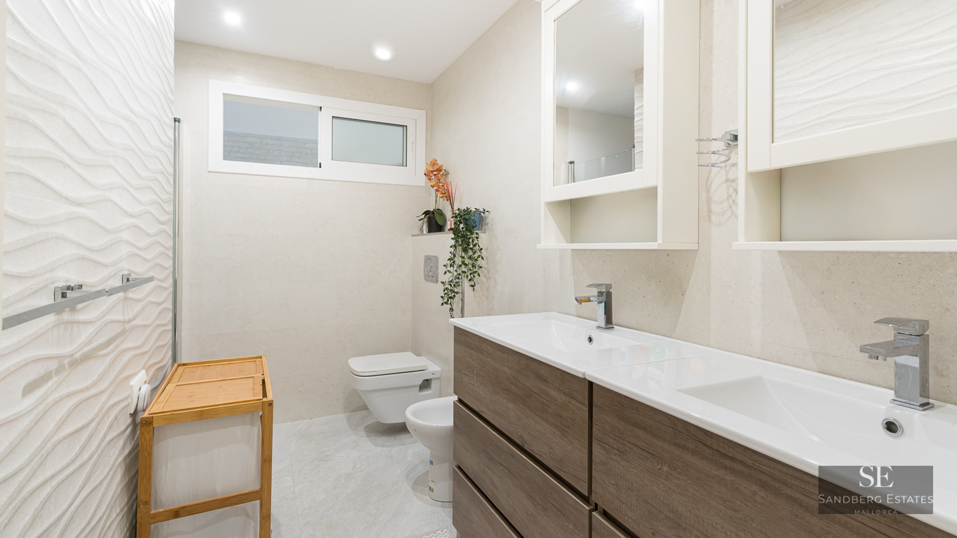 Modern bathroom with wood-finish double vanity, textured wall tiles, wall-hung toilet, and bidet.