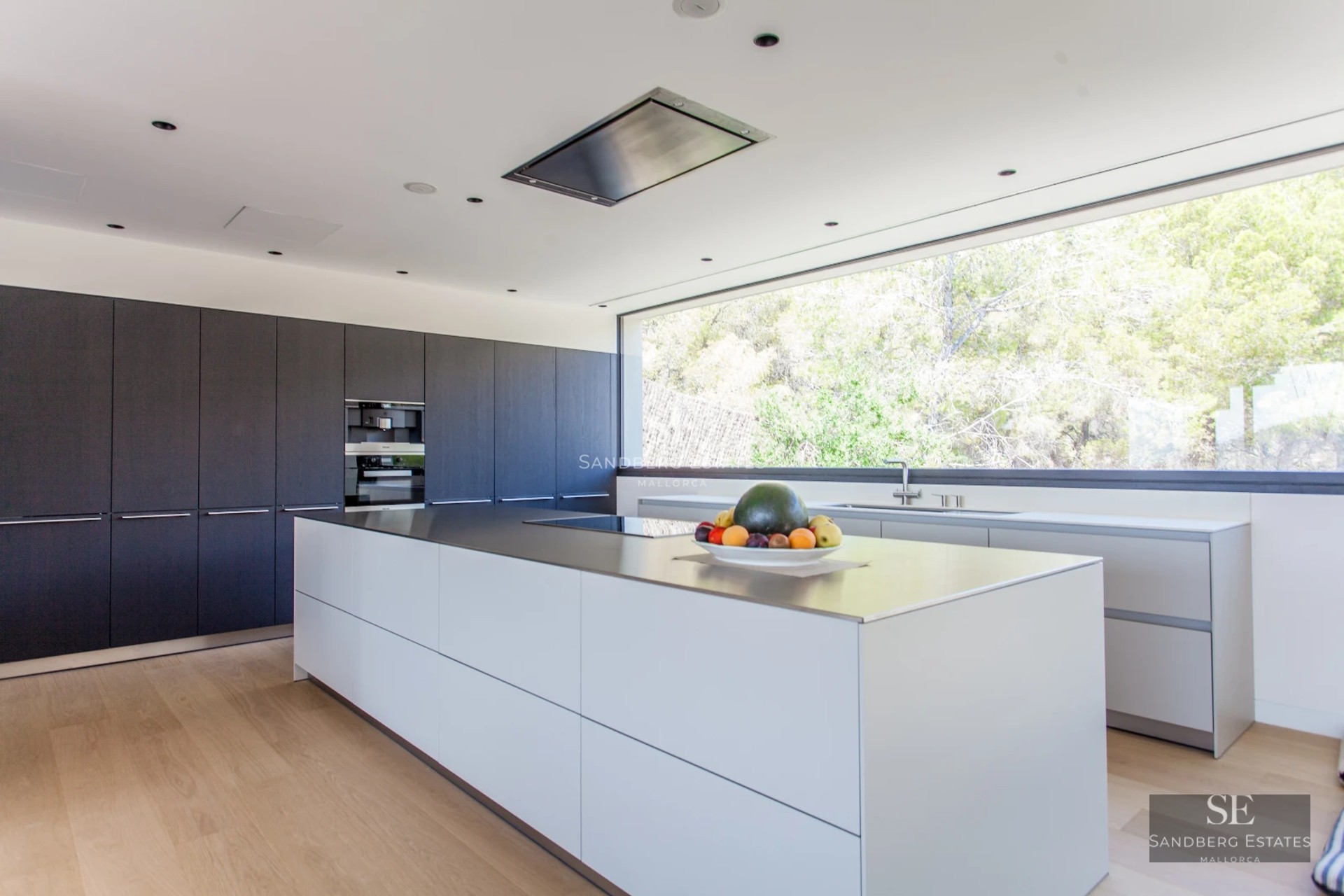 Bright living room with large windows, outdoor pool, light wood floors, and minimalist design. Beige sofa and stone details.