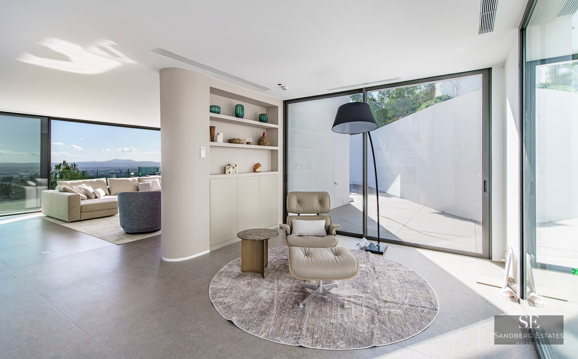 Minimalist reading nook with leather lounge chair and floor-to-ceiling windows overlooking the city.