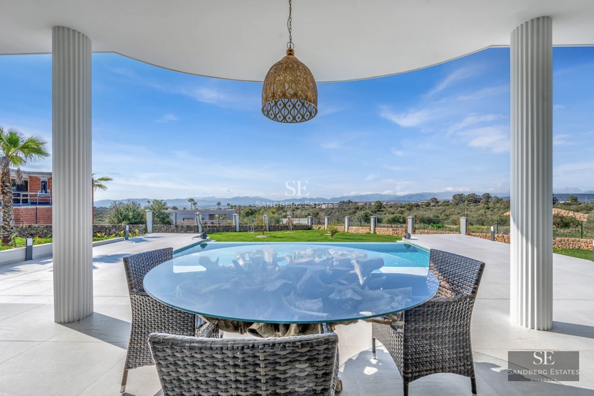 Spacious living room with large windows, pool reflecting the light. Modern design with minimalist furniture and wood accents.