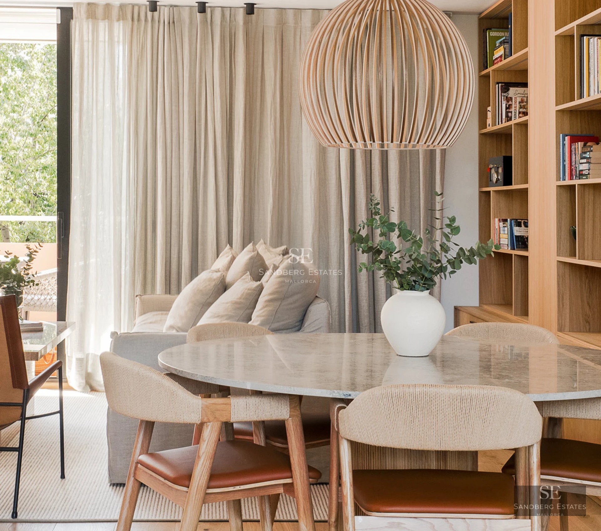 Modern penthouse featuring a glass-enclosed balcony, sea views, and a minimalist design. Bright interior with wood floors and designer furniture.