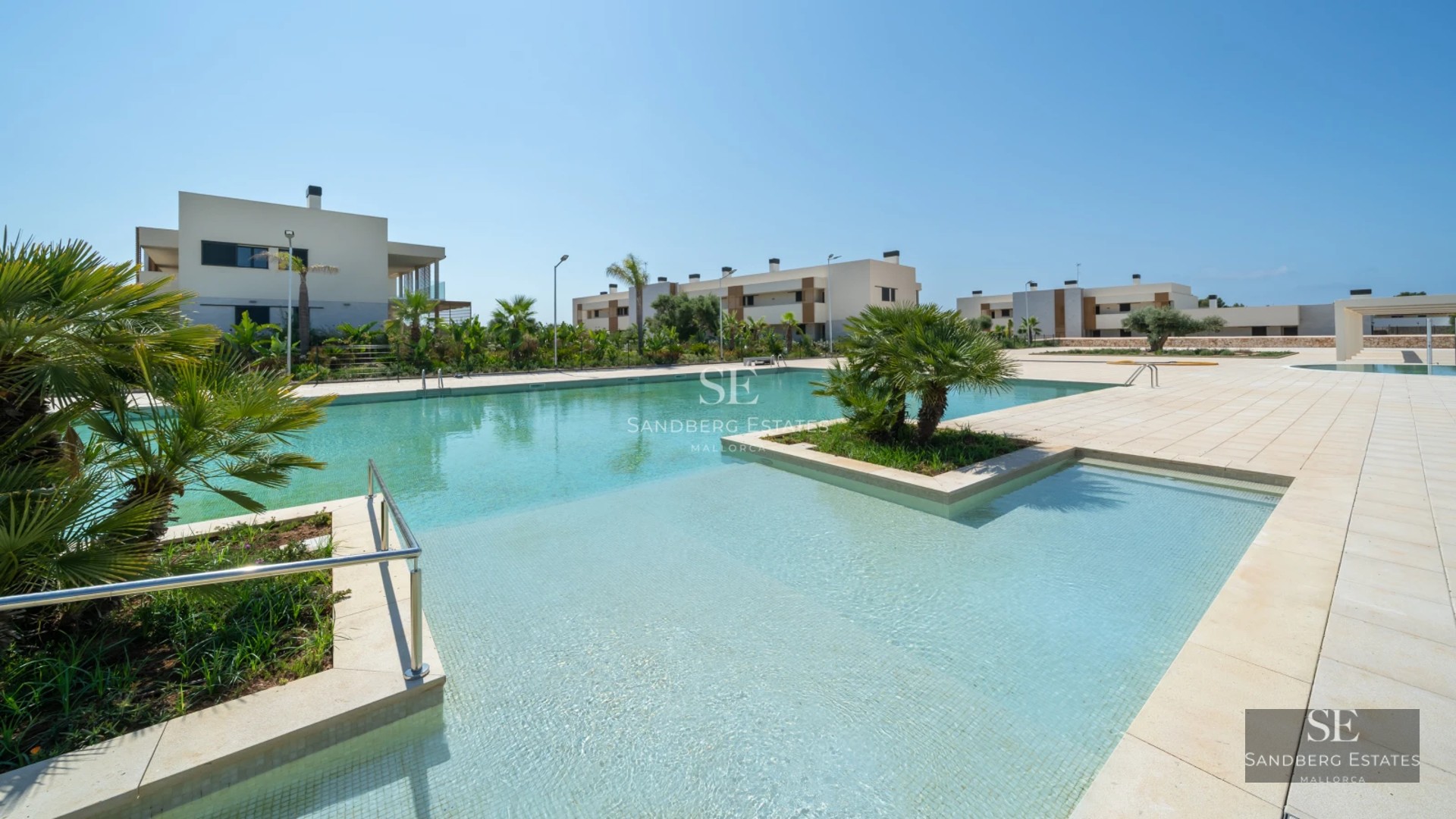 Wide view of a luxurious house featuring a turquoise pool and lush garden. Modern design, palm trees, and clear sky.