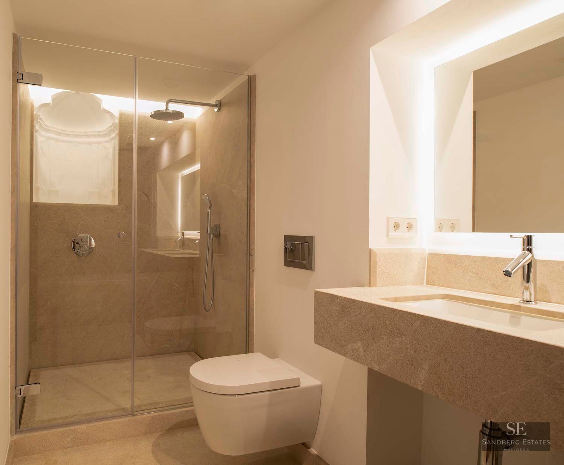 Modern bathroom featuring a glass-enclosed shower, a floating toilet, and a stone vanity with a backlit mirror.