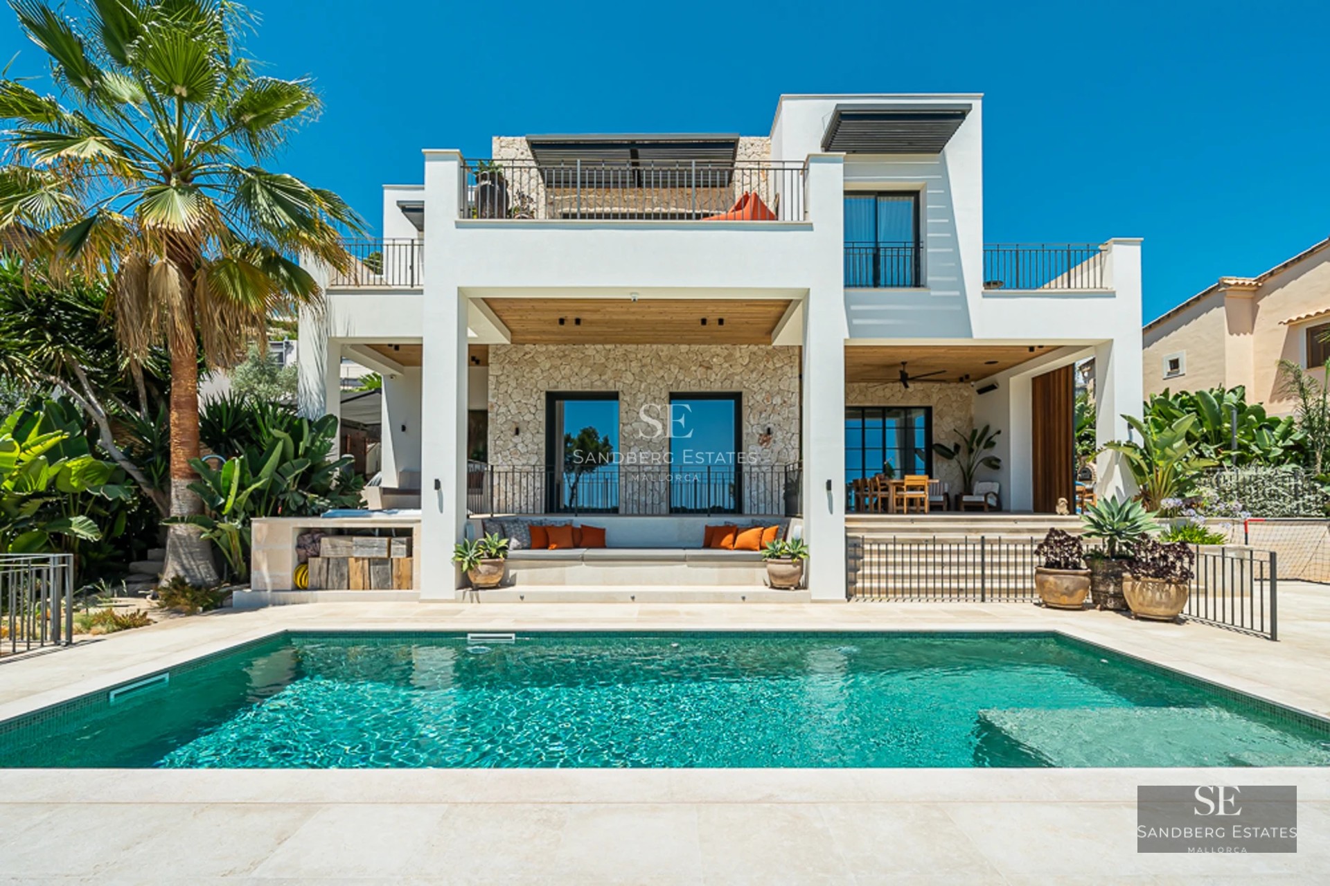 Vue extérieure d'une villa moderne avec piscine à débordement, jardin paysager et grandes baies vitrées. Design architectural minimaliste.