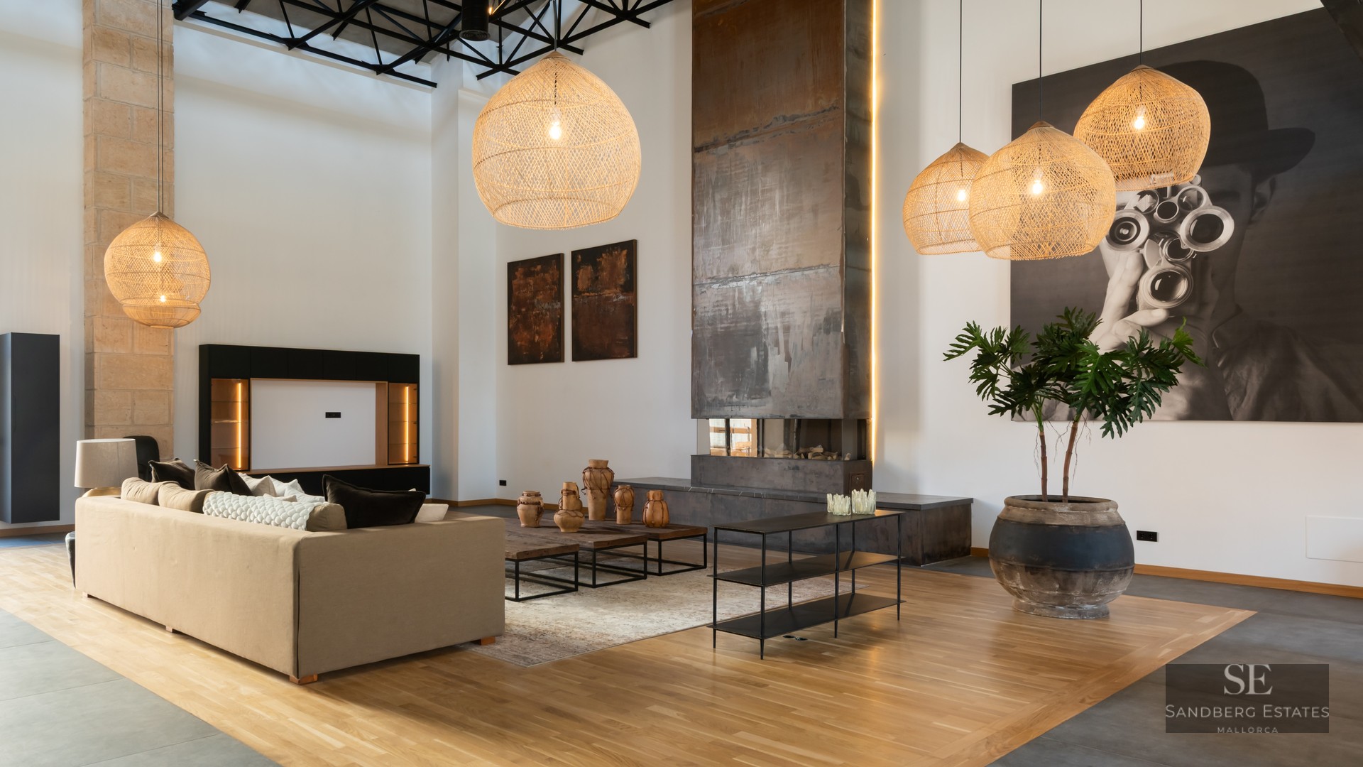 Spacious living room with high ceilings, large metal fireplace, wicker pendant lights, and modern beige sofa.
