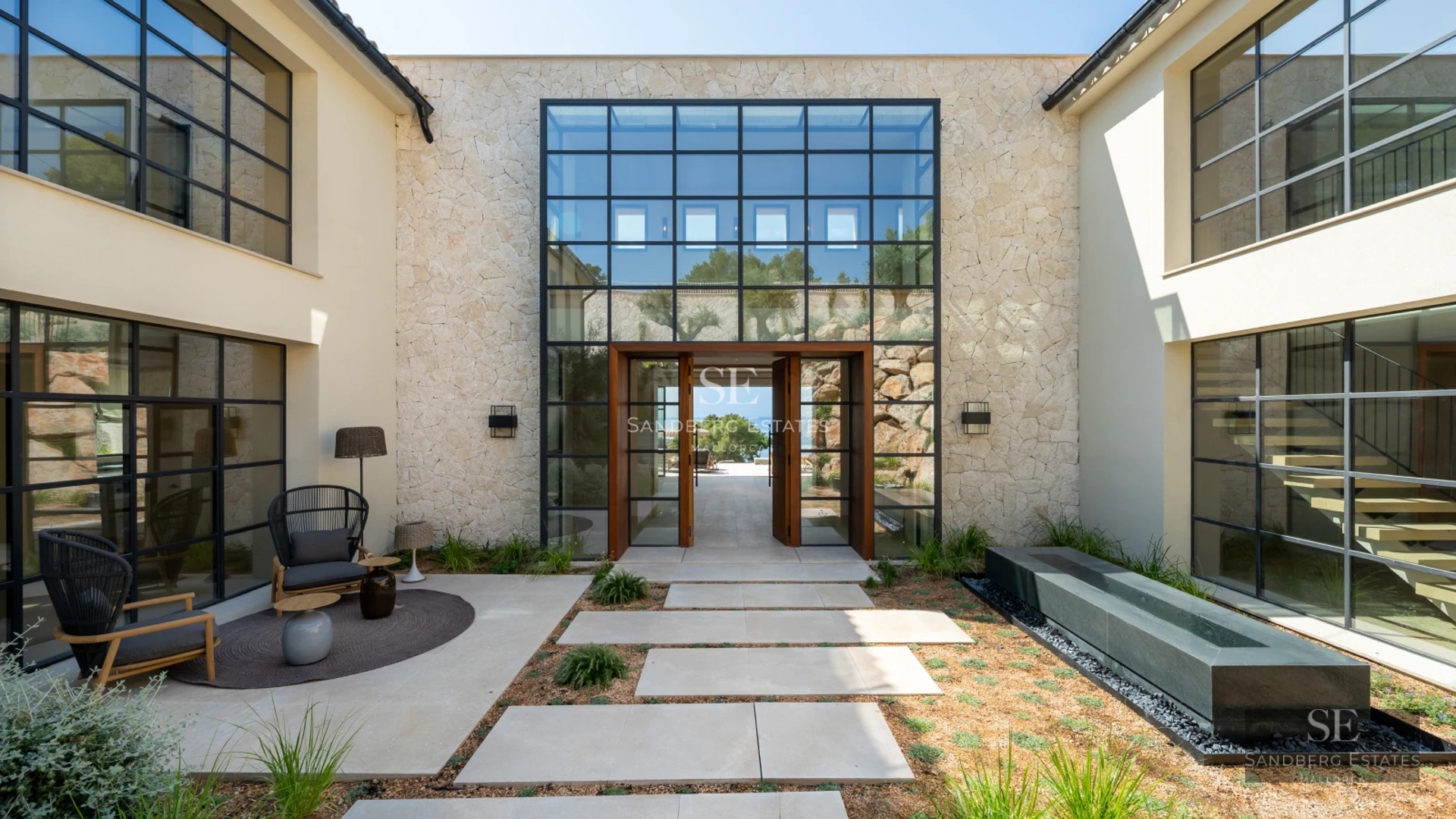 Spacious living room featuring floor-to-ceiling windows, natural light, wood floors, light-colored sofas, and city views. Modern and elegant design.