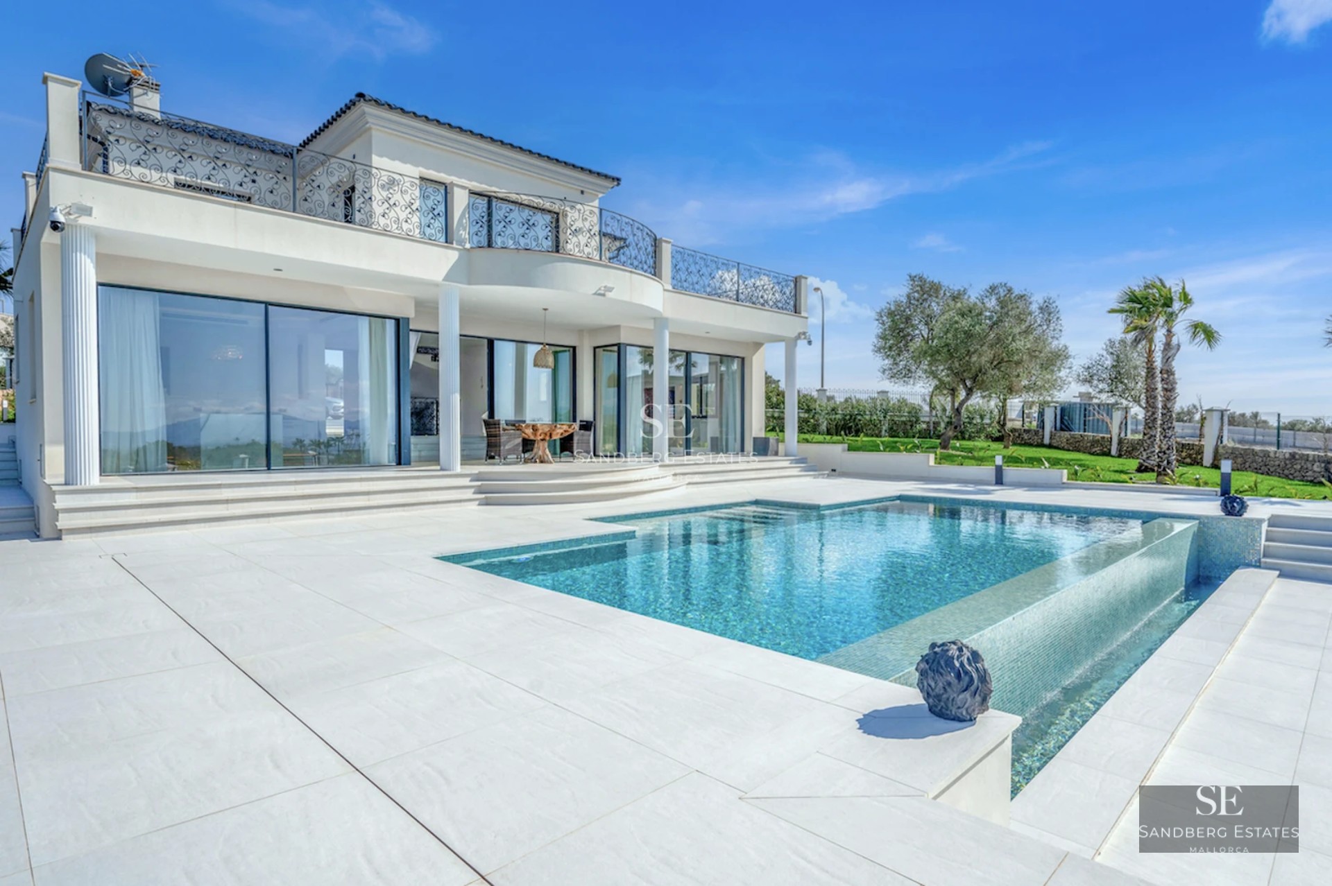 Spacious living room with pool view. Modern design, natural light, neutral colors. Light wood floors and elegant furniture.