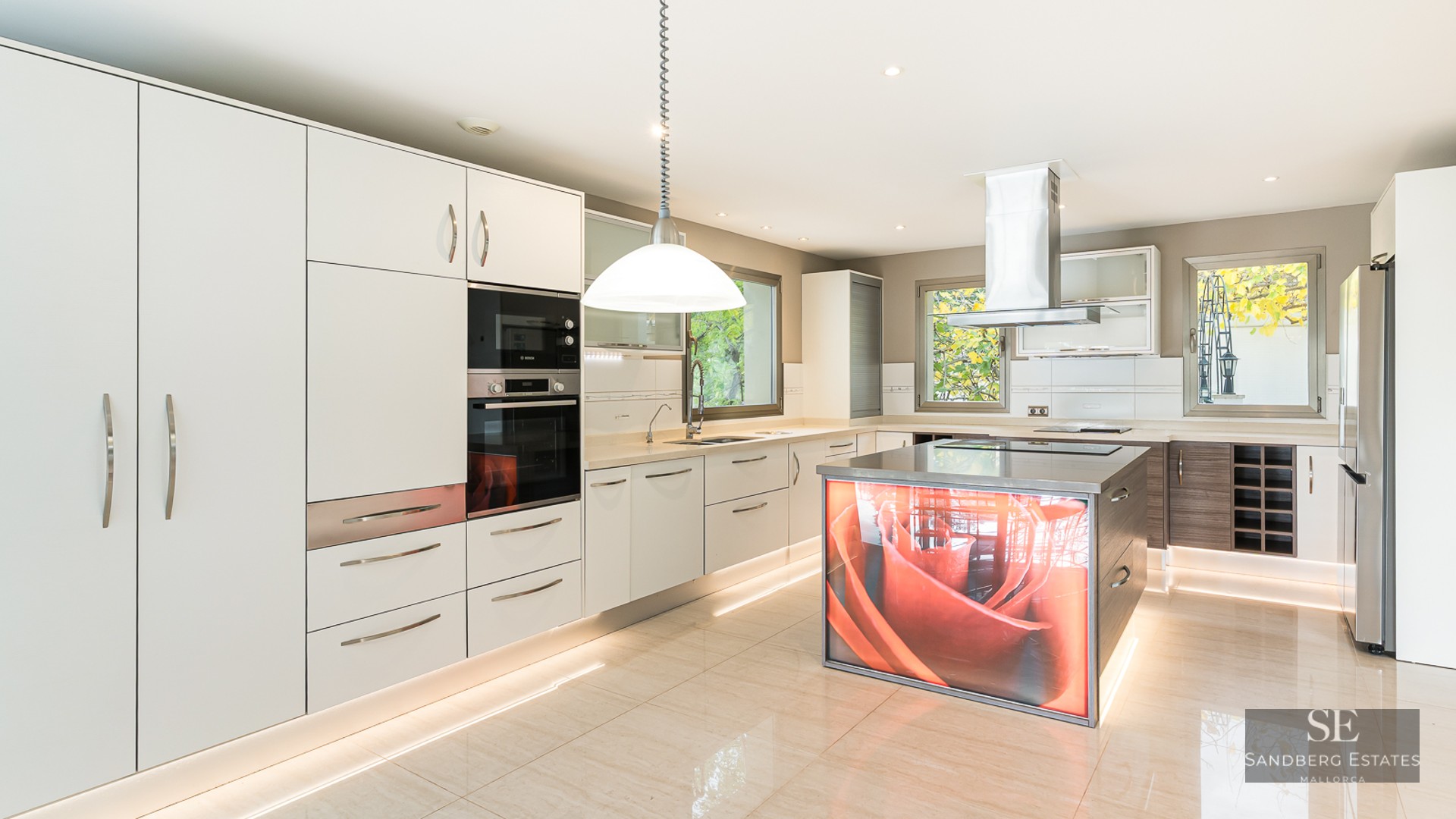 A bright, modern kitchen with white cabinets, stainless steel appliances, and a unique illuminated orange rose island.