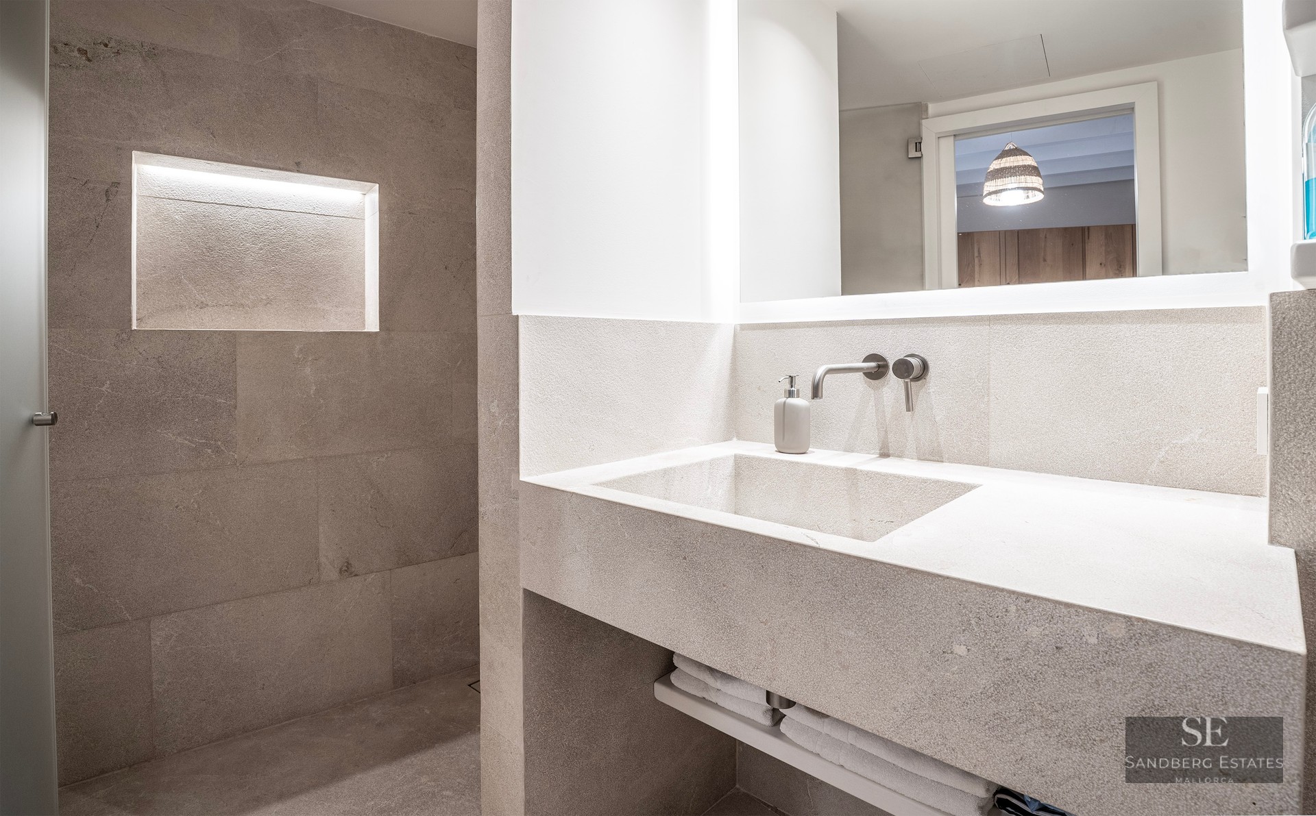 Modern bathroom featuring an integrated stone vanity, backlit mirror, and a walk-in shower with a lighted recessed niche.