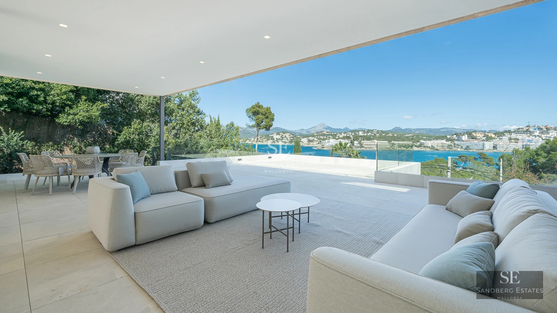 Bright living room opening to a balcony with sea view. Modern design, wood floors, minimalist decor and abundant natural light.