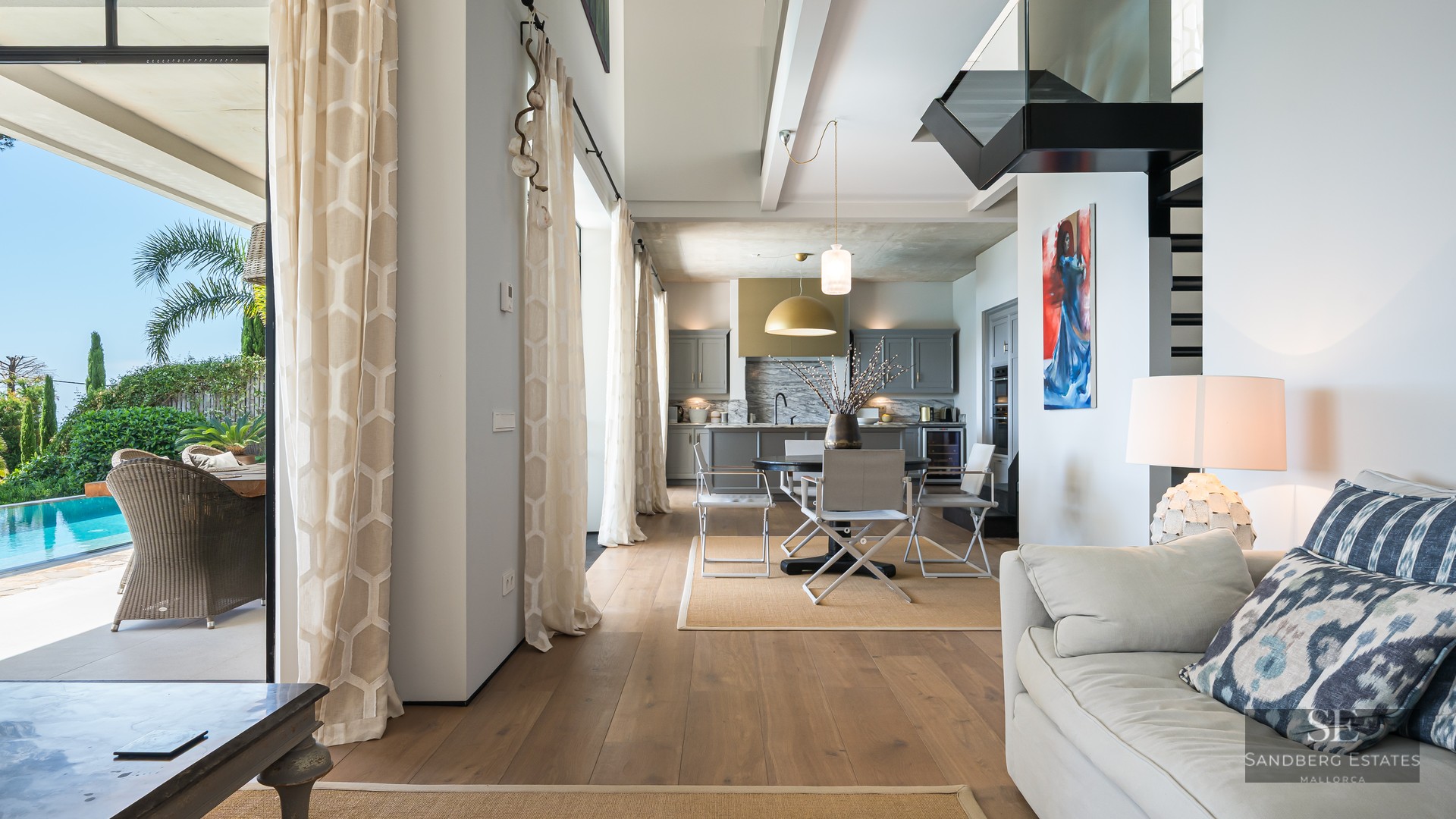 Bright open-plan living and dining room with wood floors, leading to an outdoor terrace and swimming pool.