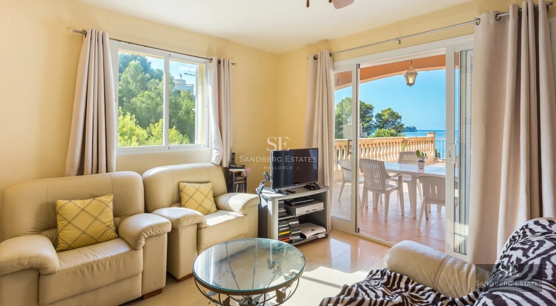 Bright interior with large windows, light wood flooring, and modern furniture. Panoramic sea views.