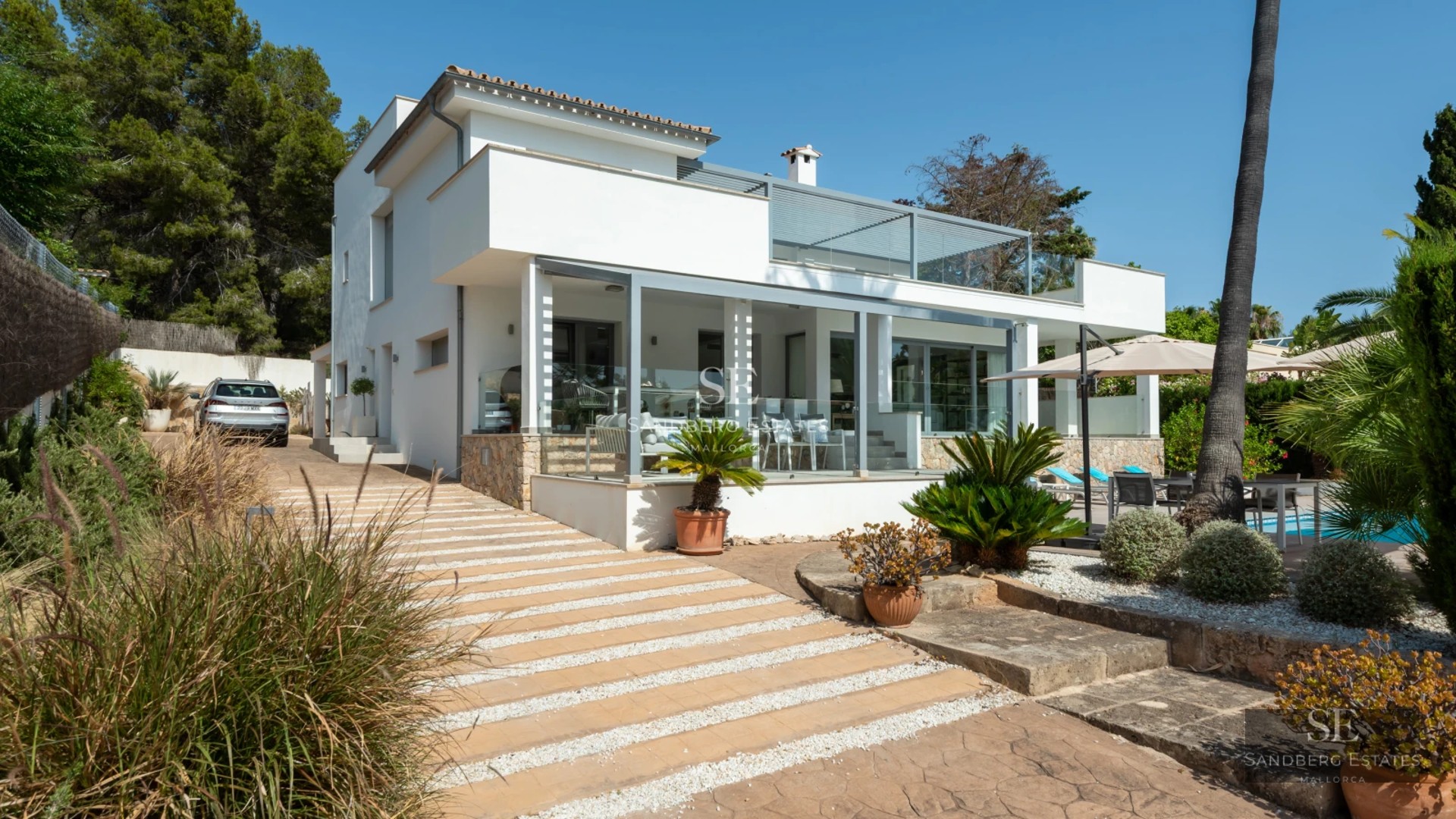 Exterior of a modern villa featuring an infinity pool, spacious terraces, and lush garden. Minimalist architecture, panoramic windows, and landscaping.