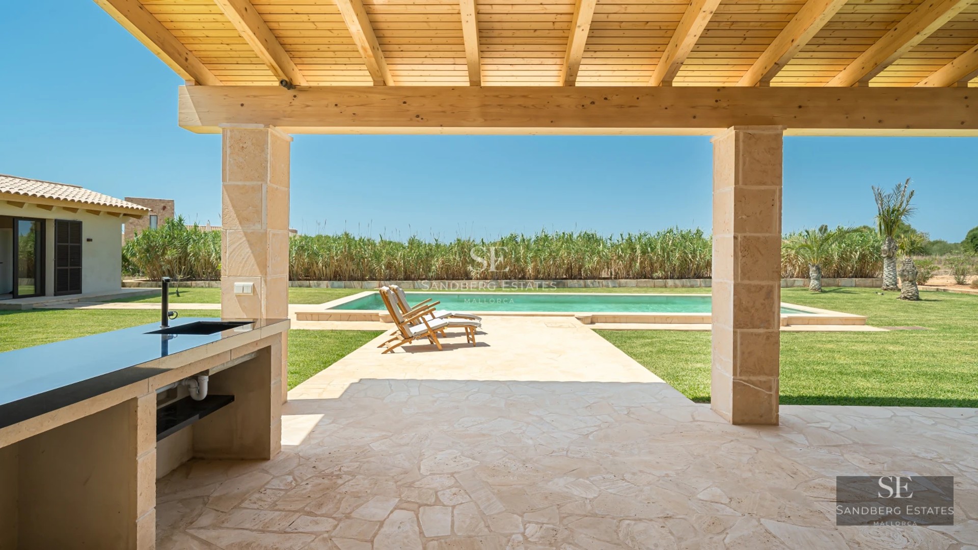 Spacious terrace with infinity pool, sun loungers, and panoramic views. Modern design with wooden floors and glass railing.