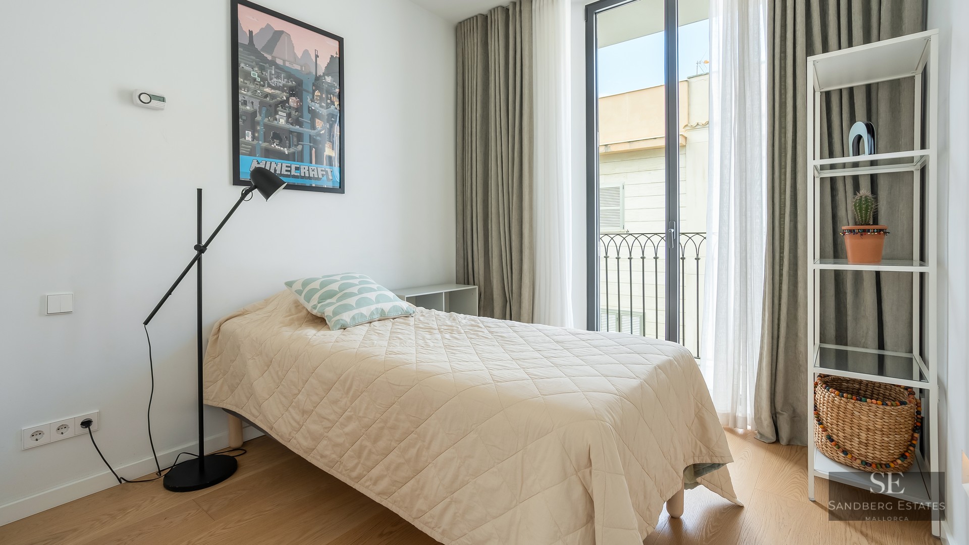 Bright bedroom with single bed, Minecraft poster, black floor lamp, and glass balcony door.
