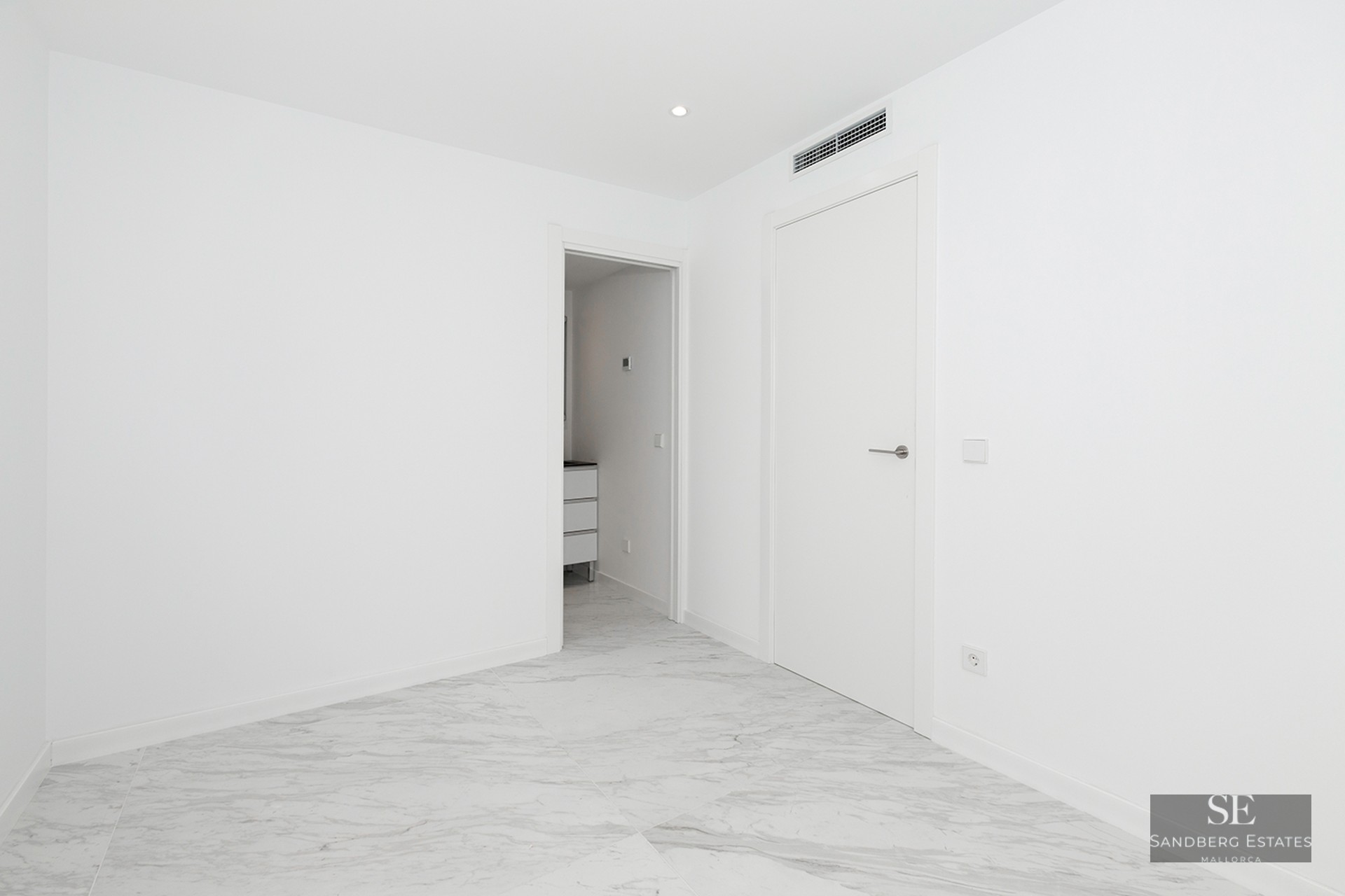 Bright empty room with white walls, polished grey-veined marble floors, and modern white doors.
