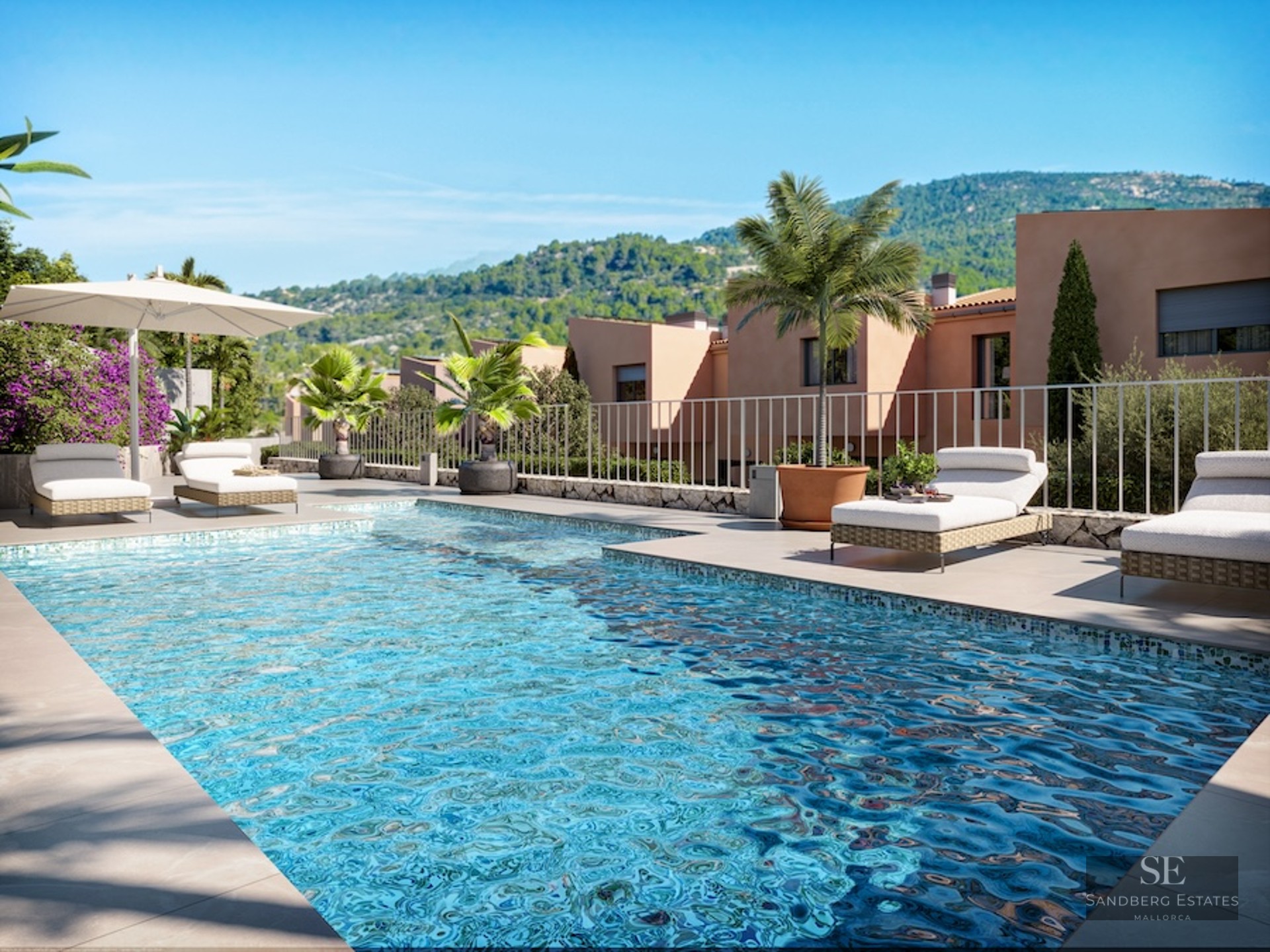 Turquoise swimming pool with sun loungers and palm trees overlooking lush green mountains under a blue sky.