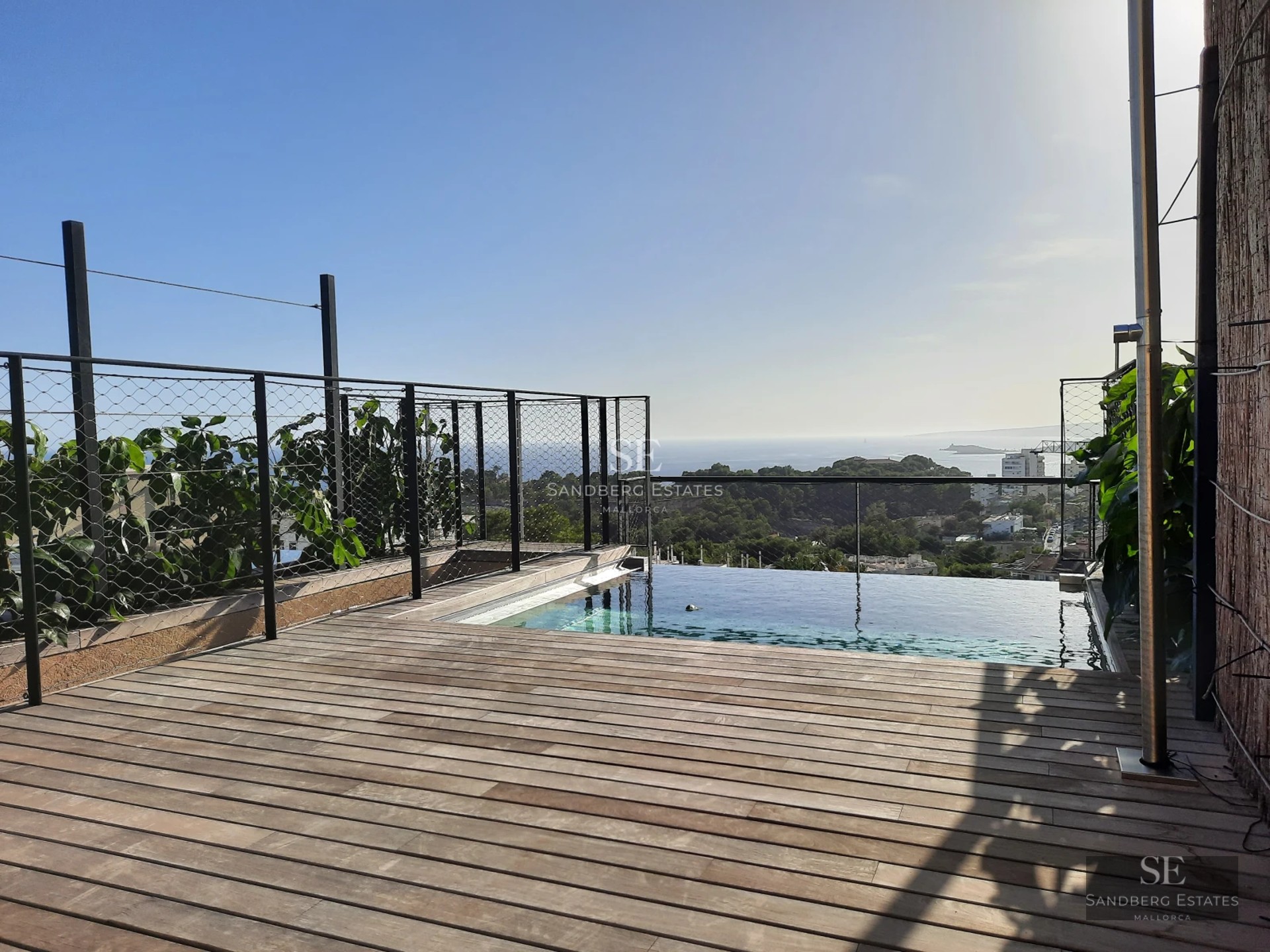 Aerial view of a modern villa with turquoise pool, surrounded by gardens and terraces. Minimalist and elegant architectural design.