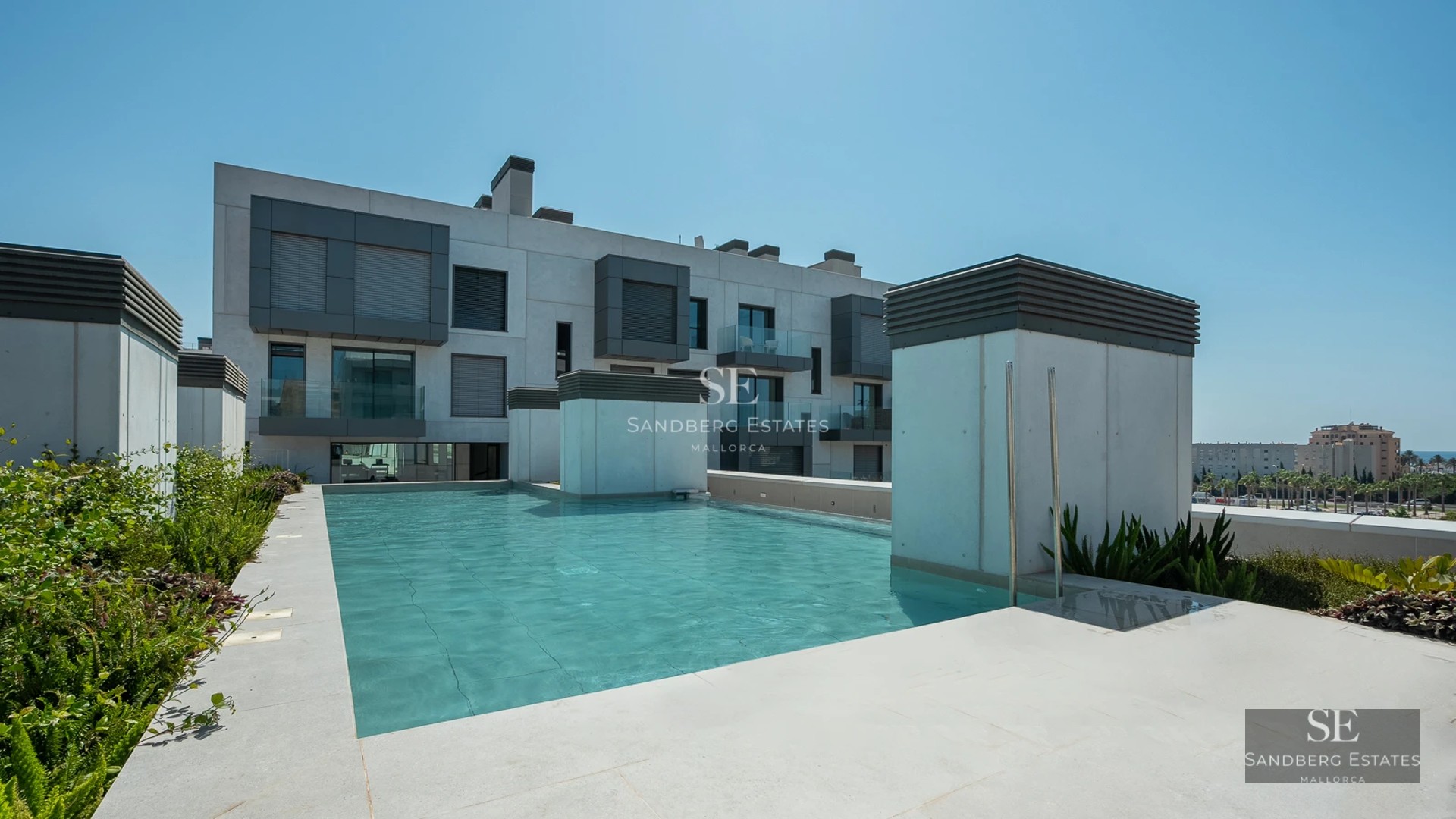 Spacious living room with large windows, light wood flooring, and panoramic sea views. Modern sofa and minimalist decor.