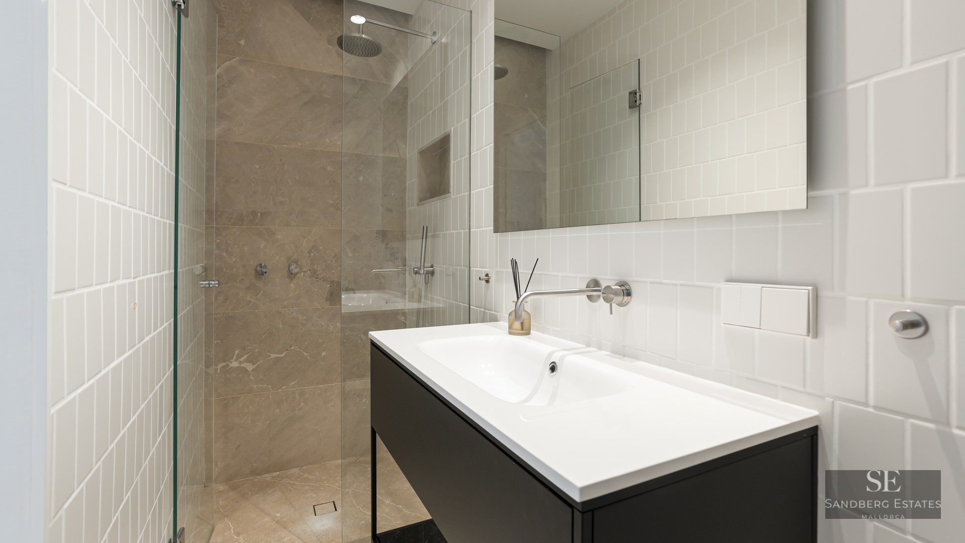 Modern bathroom with white vertical tiles, a black vanity, and a glass-enclosed stone walk-in shower.