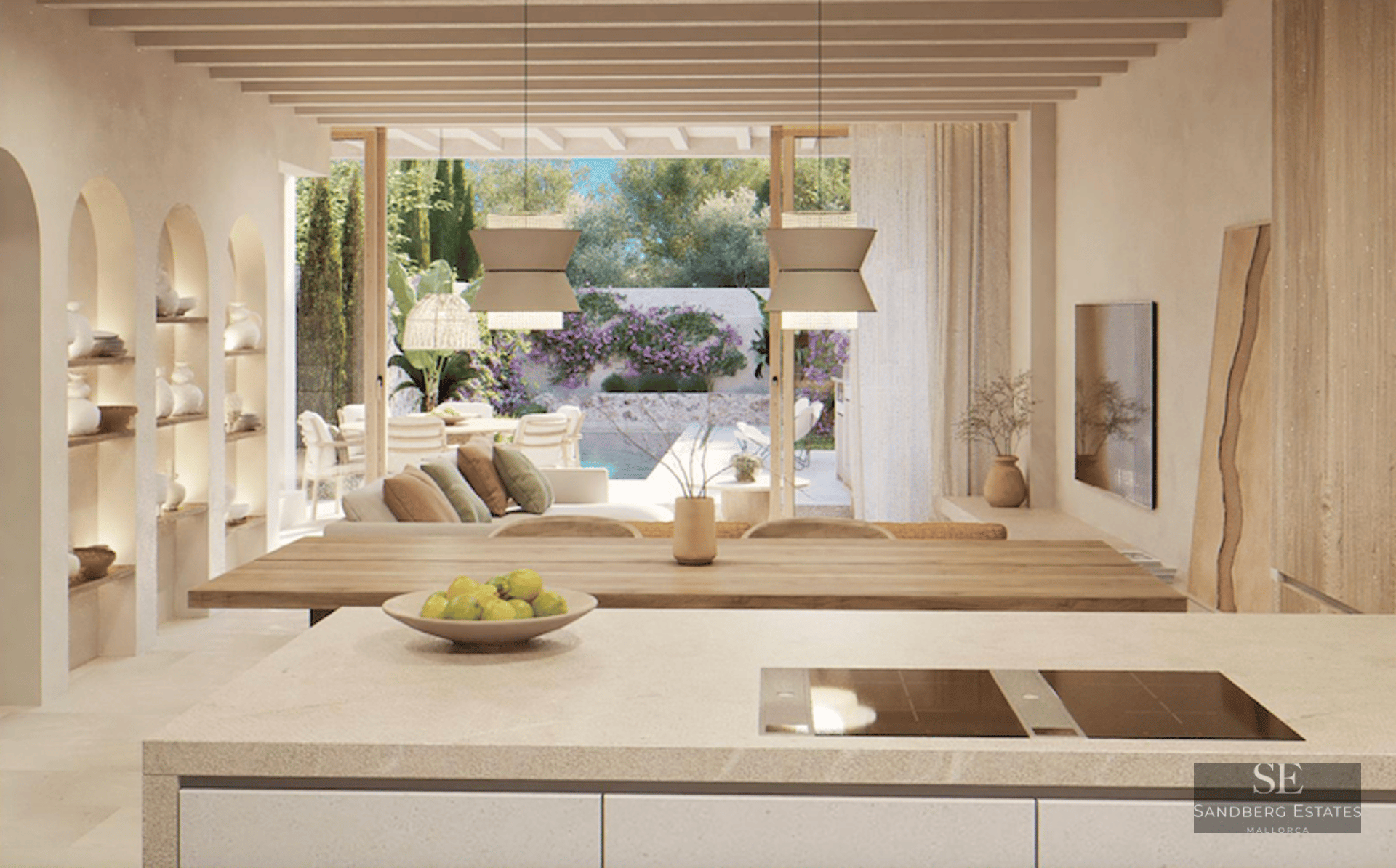 Open-plan space with a kitchen island, wooden beams, and views of a terrace with a pool and garden.