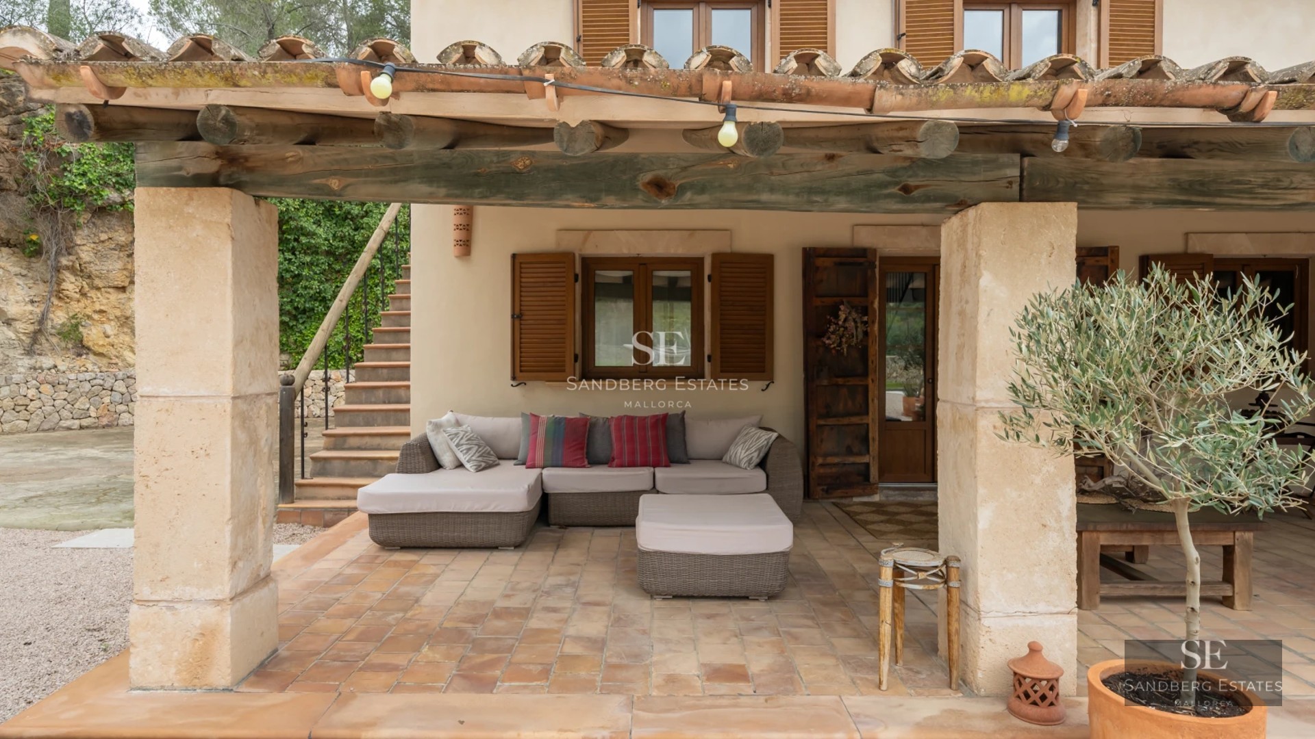 View of a bright blue swimming pool surrounded by a terrace with sun loungers and a lush garden. Modern architecture with large windows.