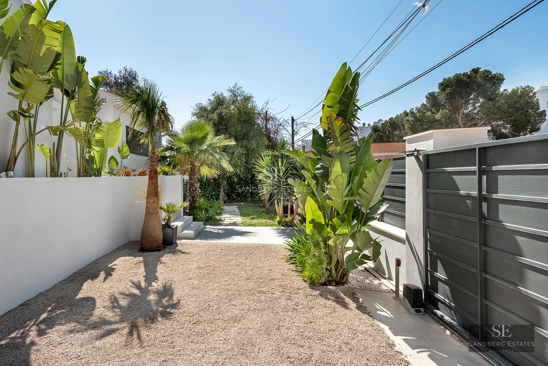 Exterior view of a modern villa with pool, large windows, gardens, and minimalist architecture.