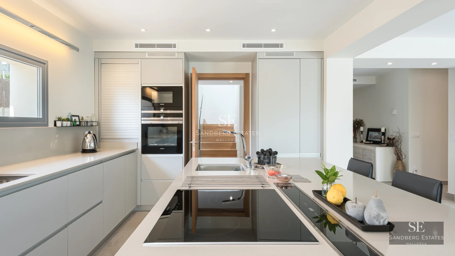 Spacious living room featuring panoramic windows offering a sea view. Modern sofa, textured rug, and ambient lighting.