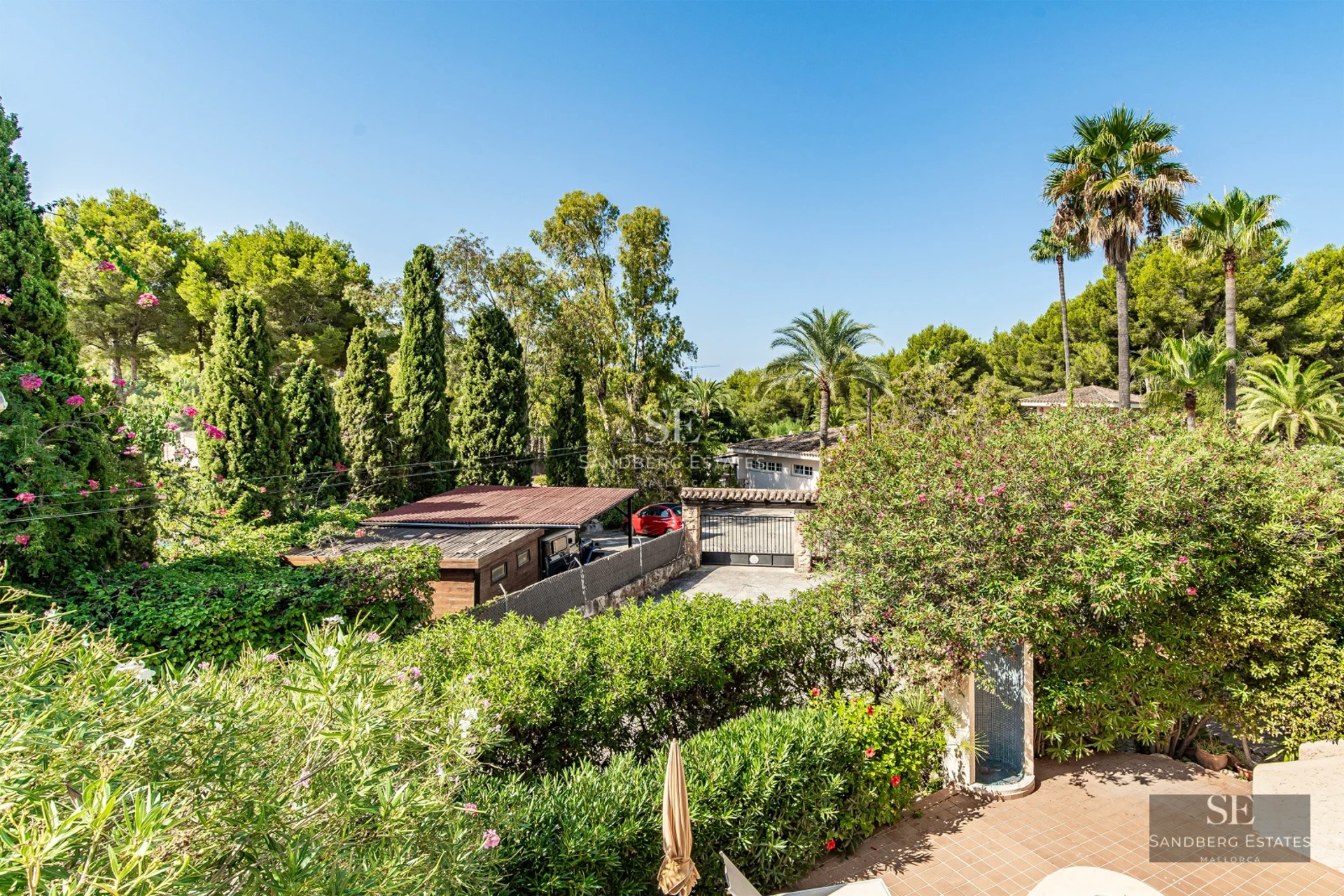 Panoramic view of a turquoise swimming pool surrounded by a modern house with large windows and a lush garden.