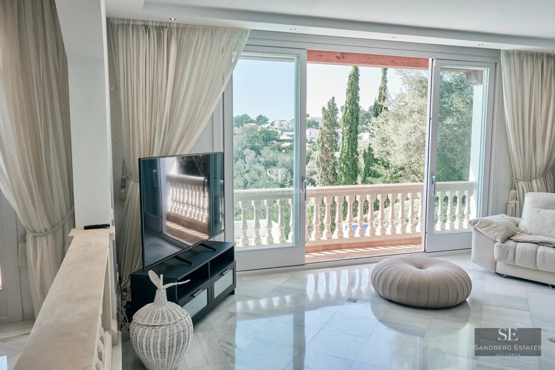 View of infinity pool with modern design and sun loungers. Well-maintained garden with lush vegetation. Clear blue sky in the background.