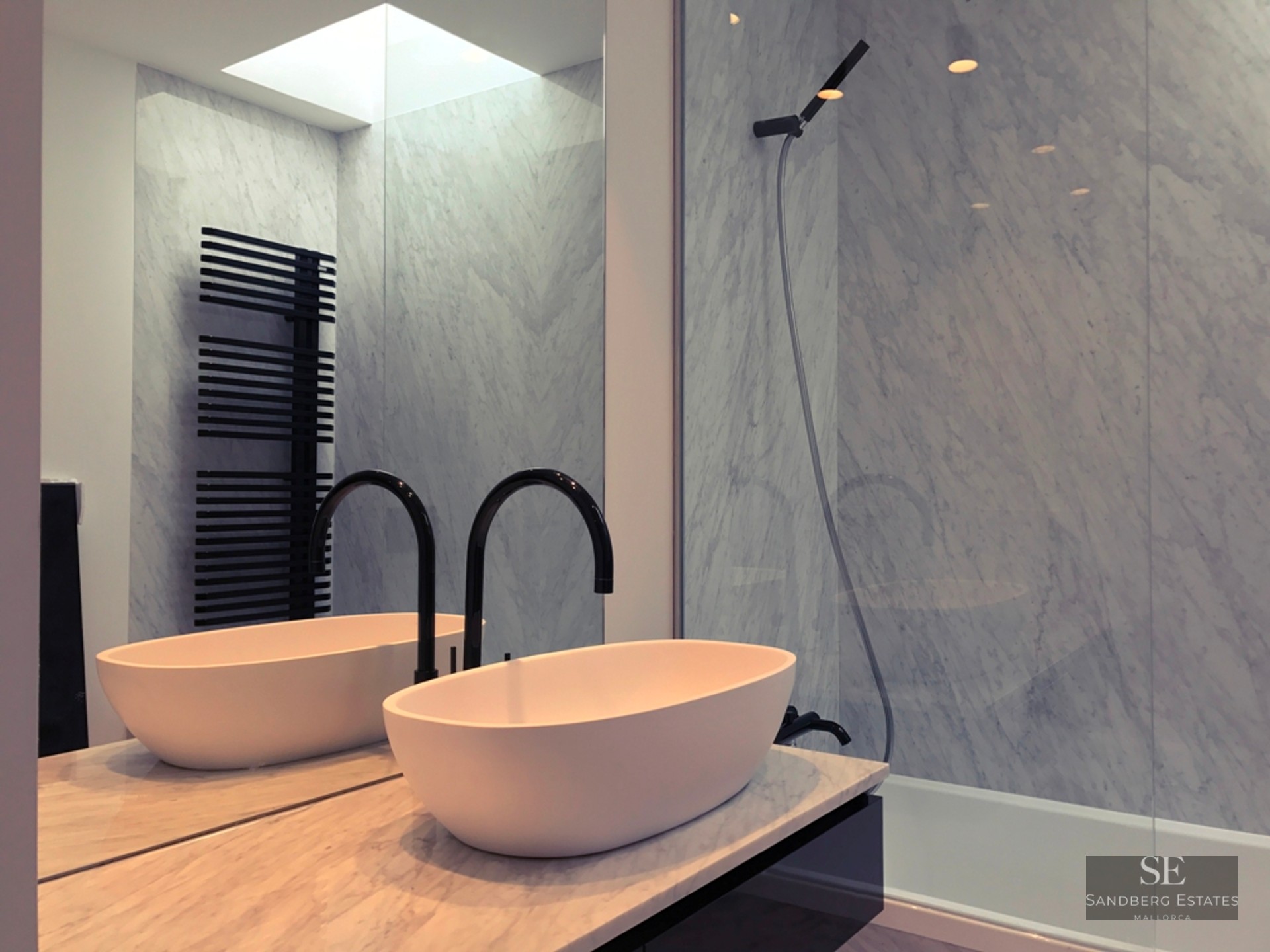 Minimalist bathroom featuring a white vessel sink, black curved faucet, and floor-to-ceiling marble walls.