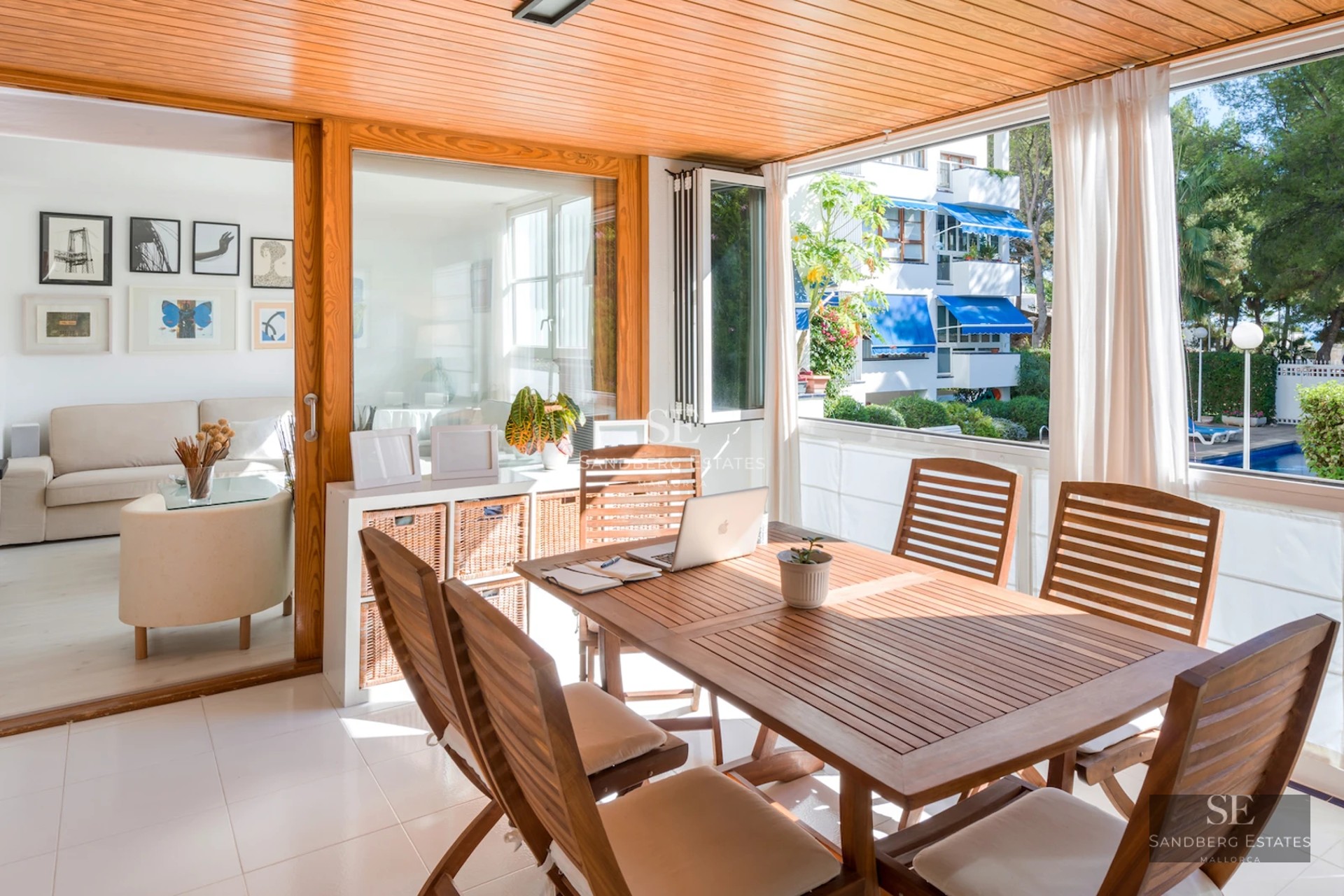 Spacious balcony with ocean views from a modern apartment. Stylish outdoor furniture, light wood flooring and glass railing.