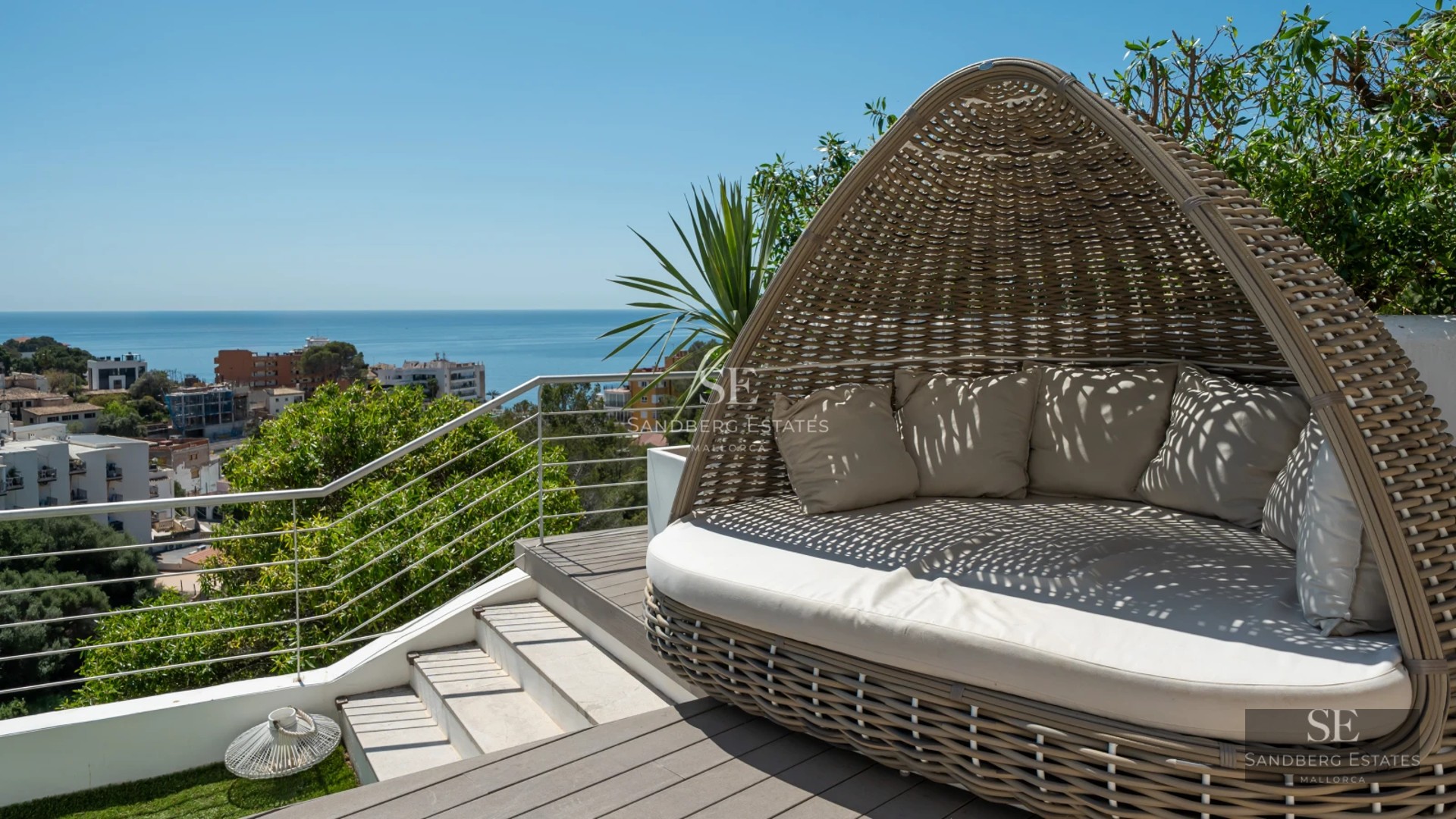 Pool view with loungers and umbrellas, surrounded by lush greenery and a modern house.