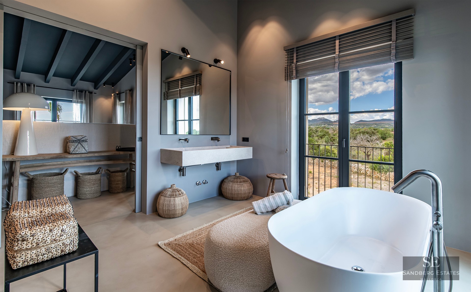 Modern master bathroom featuring a freestanding tub, floating sink, and large window overlooking a mountain landscape.