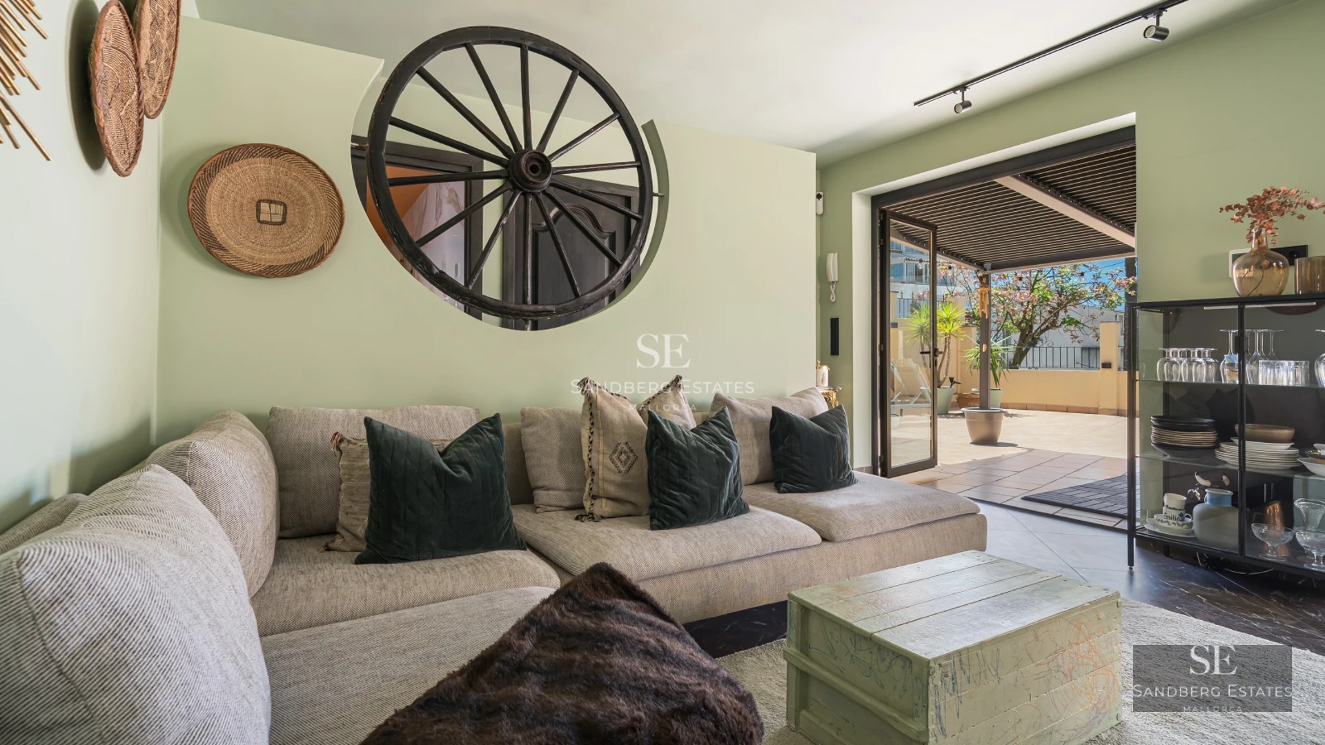 Spacious living room with floor-to-ceiling windows, light wood floors, modern furniture, and access to a terrace overlooking the pool and garden.