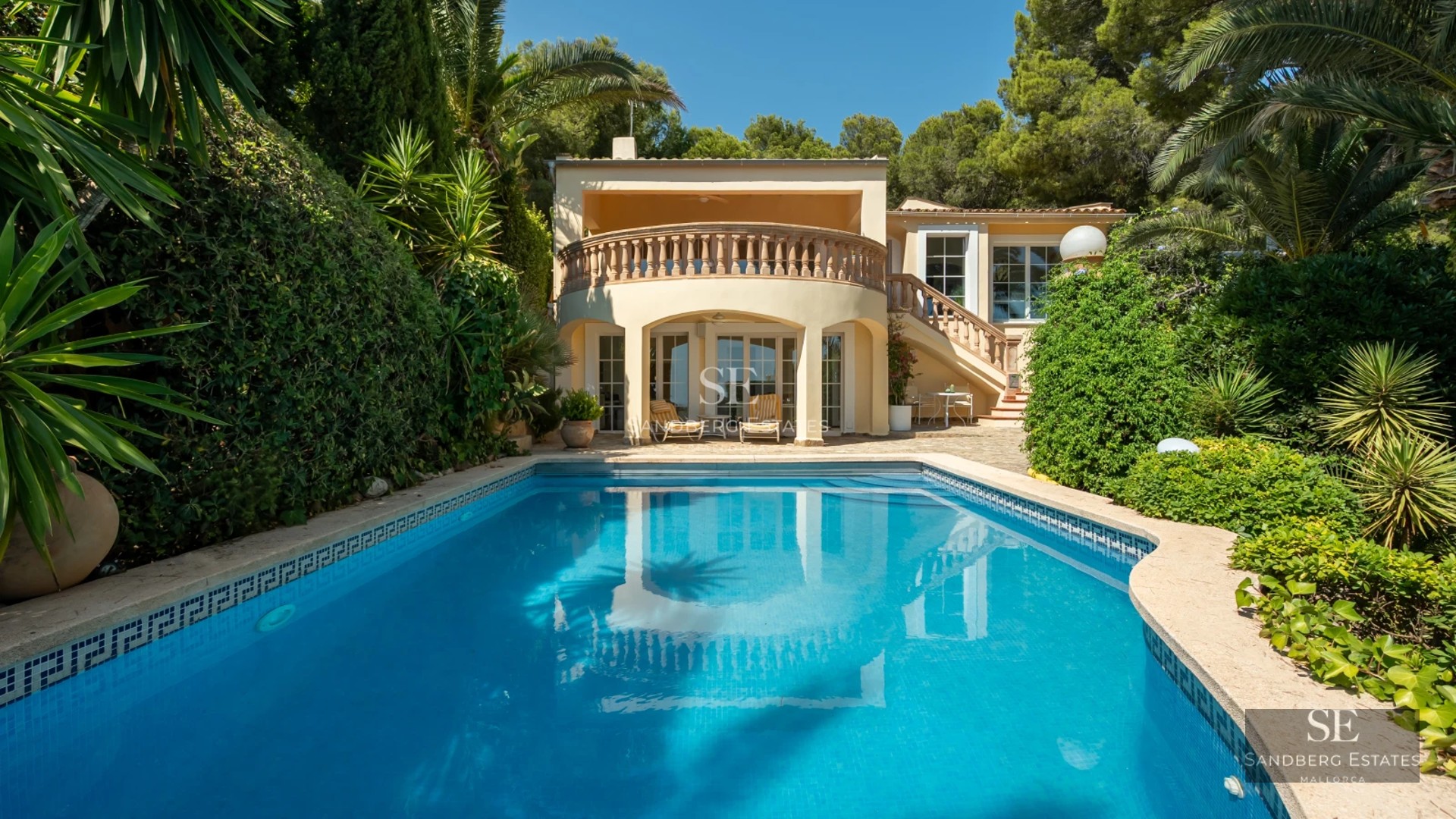 Spacious living room with floor-to-ceiling windows, designer sofas, wooden coffee table, textured rug and panoramic sea view.