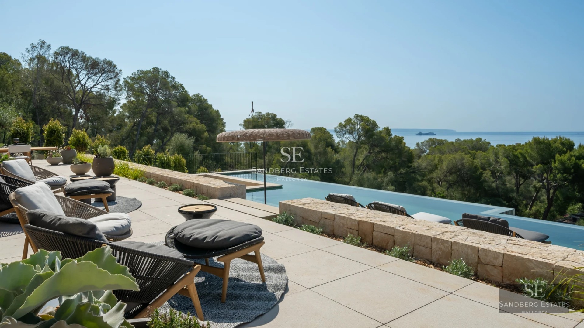 Exterior of a modern villa featuring an infinity pool, large windows, and a terrace with panoramic views. Minimalist design and lush gardens.