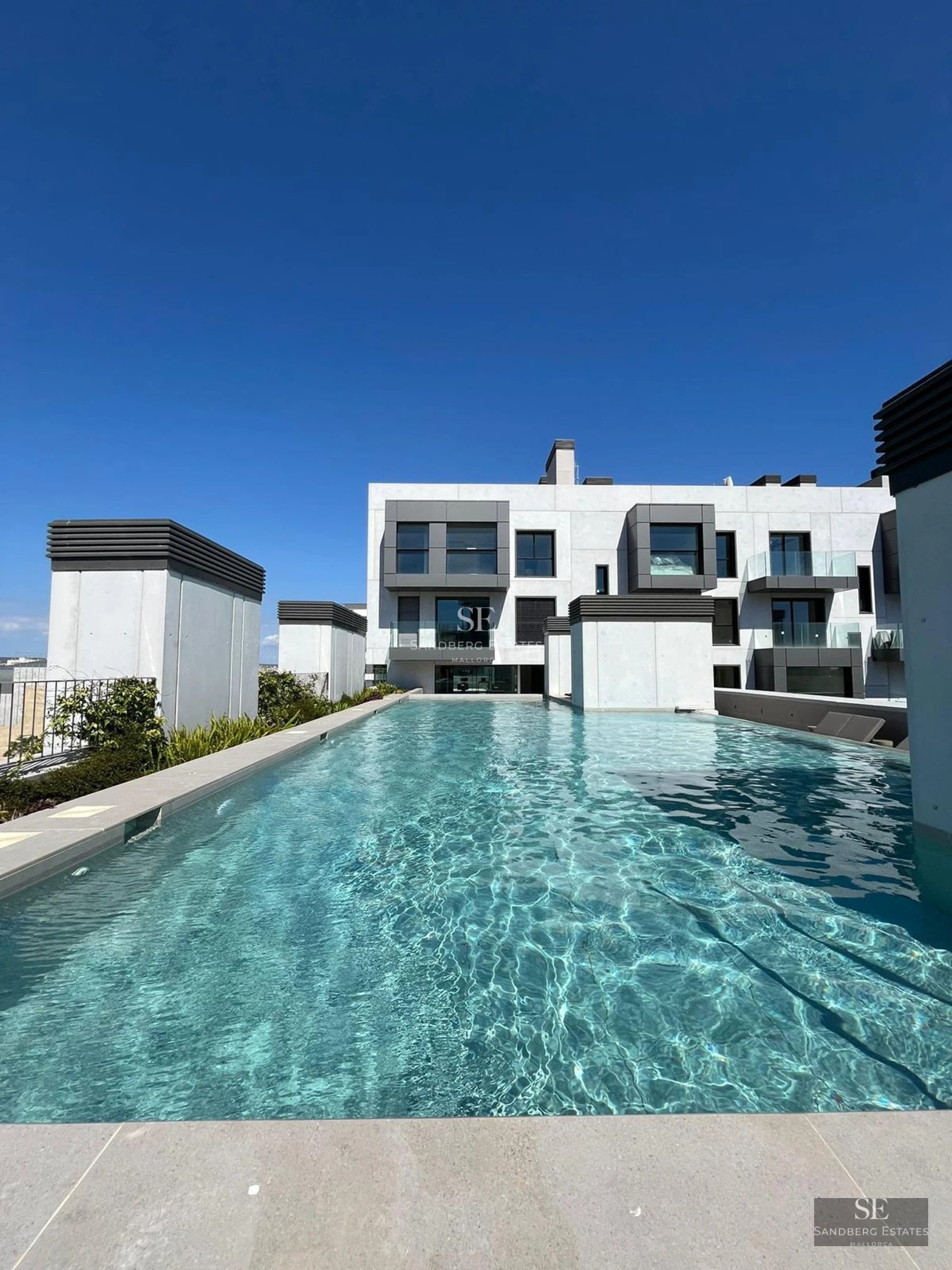 View of luxurious villa with infinity pool, lush garden, and modern architecture. Warm lighting and serene atmosphere.