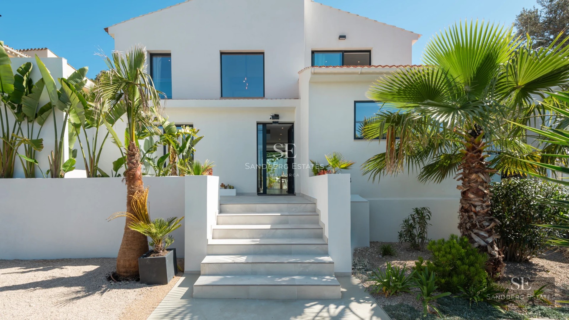 Exterior of modern villa with infinity pool, lounge chairs, garden, and panoramic views. Minimalist architecture with large windows.