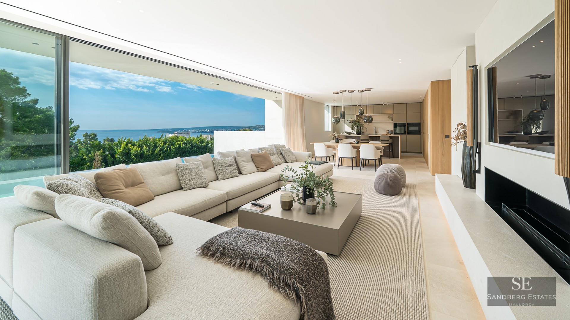 Spacious modern living room with large sectional sofa, floor-to-ceiling glass walls, and panoramic ocean views.