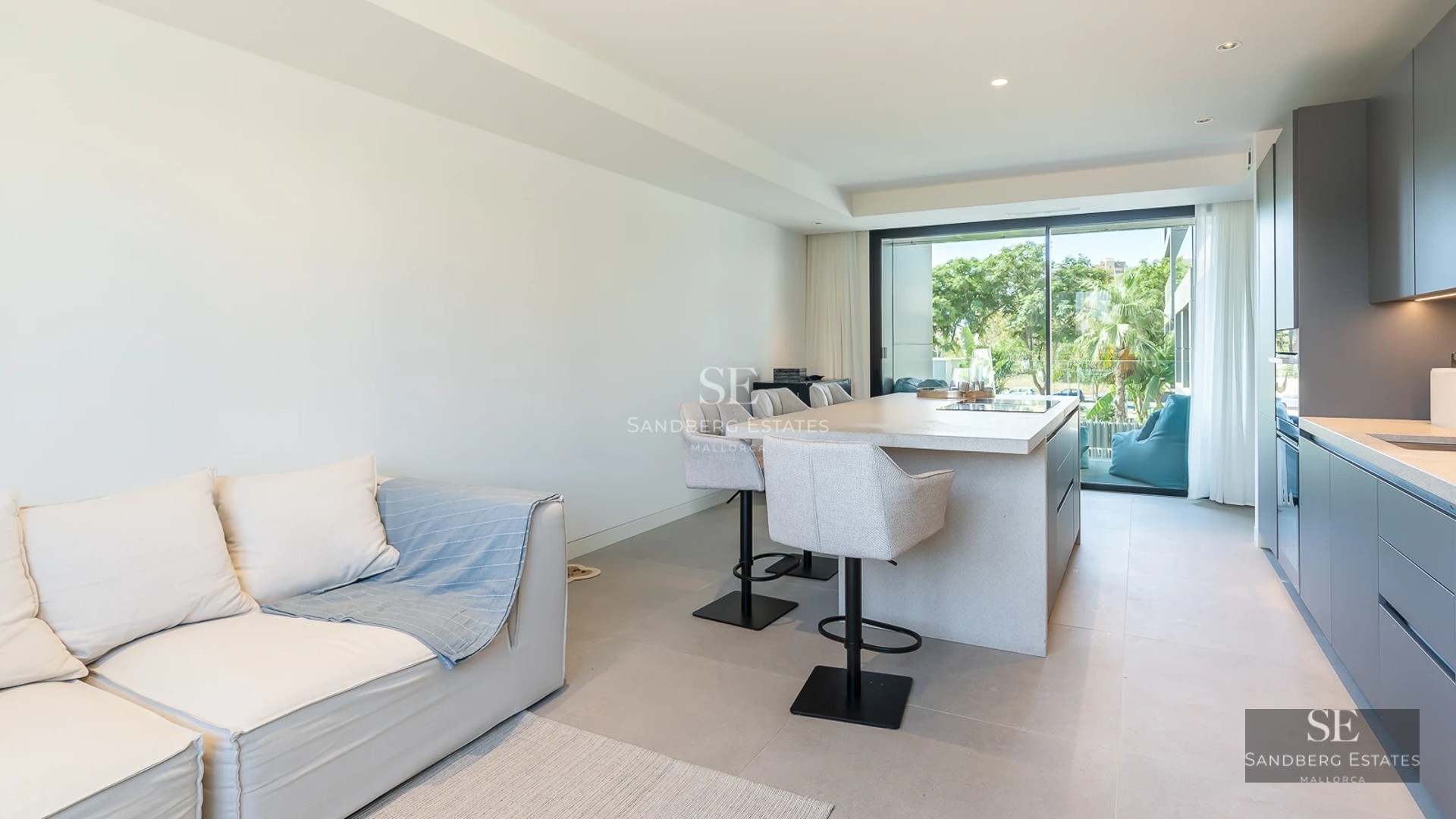 View of pool and modern house with large windows, lush greenery, and partially cloudy sky. Contemporary architecture.