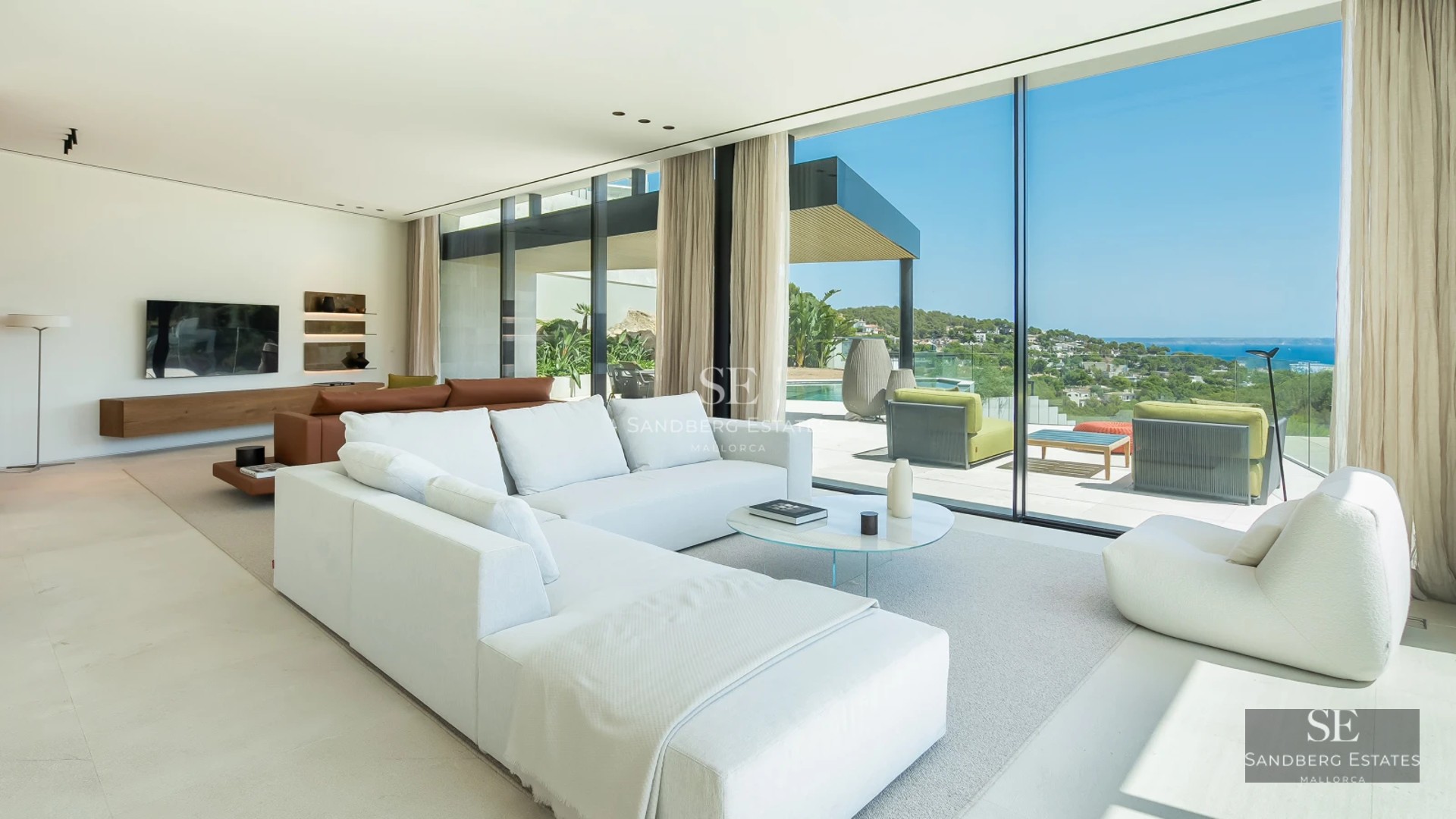View of a luxury villa with a pool, featuring large windows and a modern design. Lush garden and blue sky.