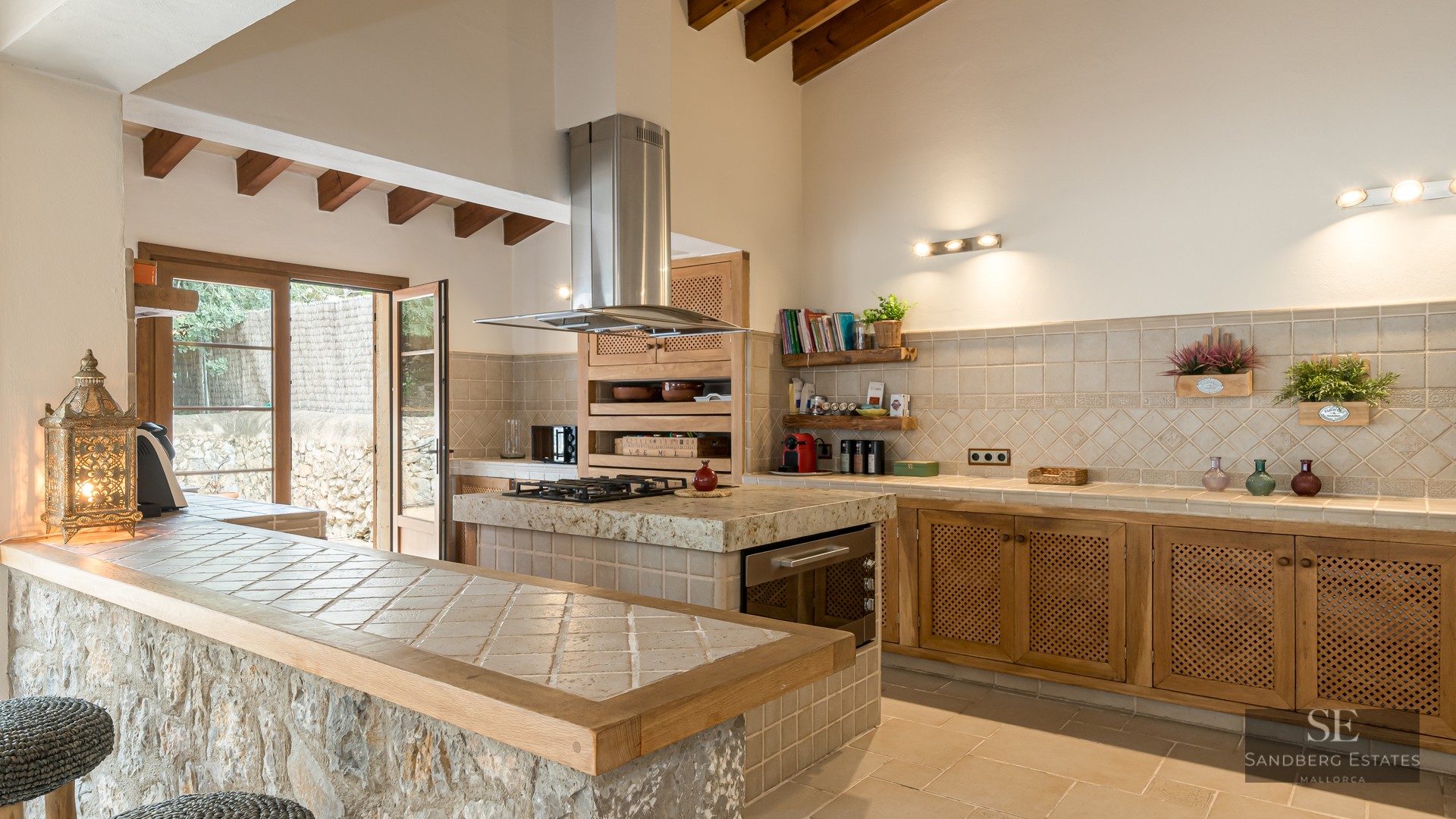 Spacious kitchen featuring exposed wood beams, a natural stone breakfast bar, and a tiled island with gas stove.