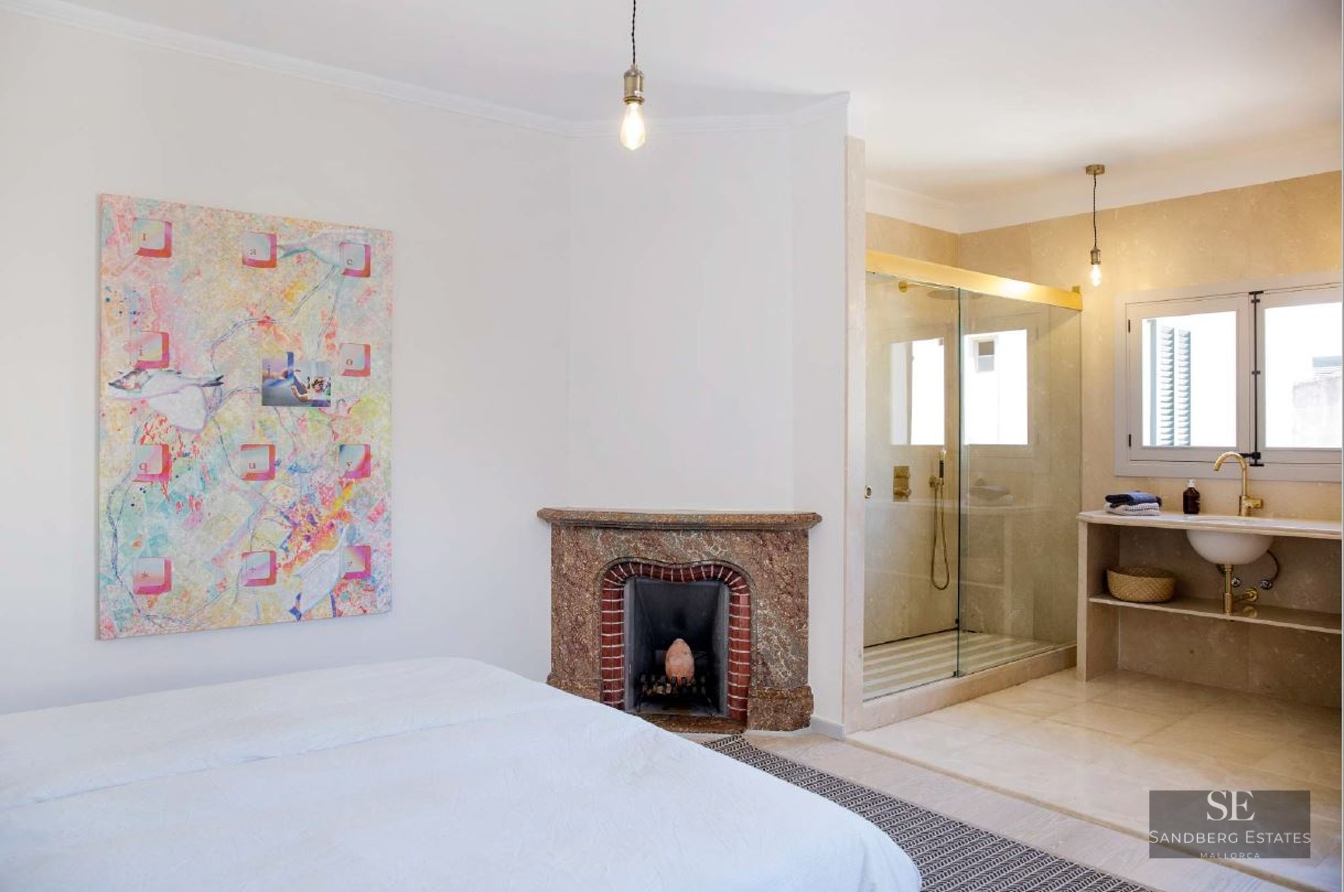 Spacious master bedroom featuring a decorative fireplace, modern art, and an integrated glass-walled ensuite bathroom.