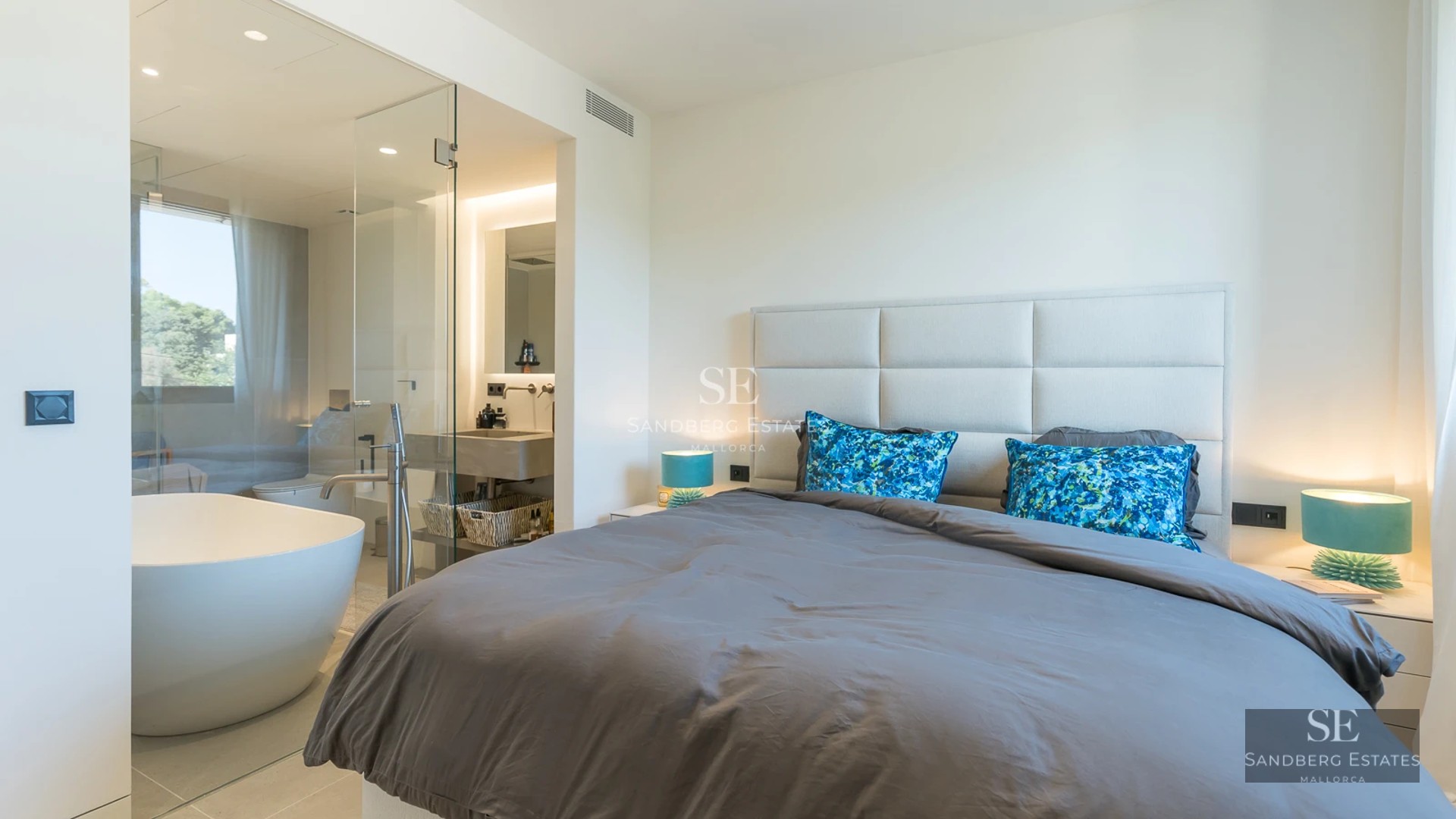 Spacious living room with large windows, natural light, light wood floors, white walls and modern furniture. Exterior view. Bright and airy.