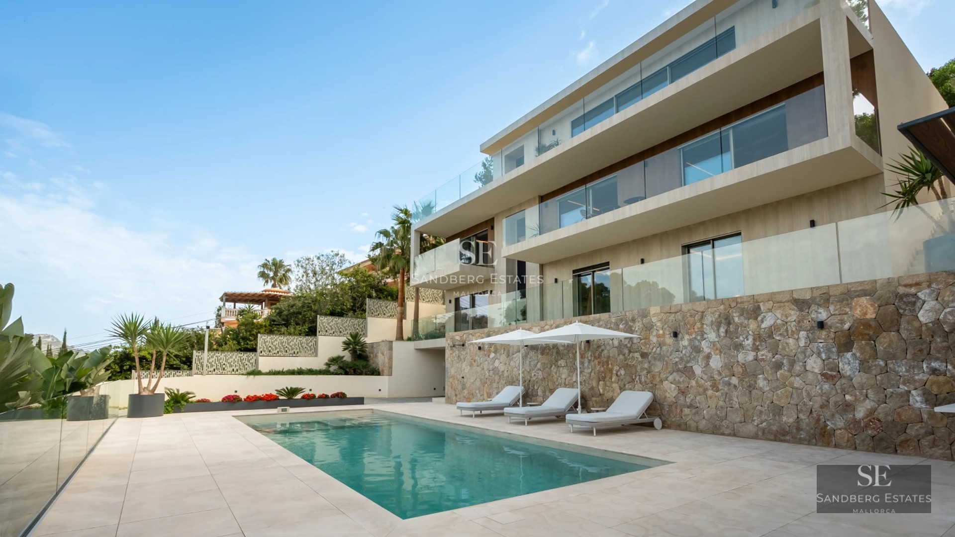 Exterior view of a modern house with a pool, manicured gardens, and large windows reflecting natural light. Minimalist and elegant design.