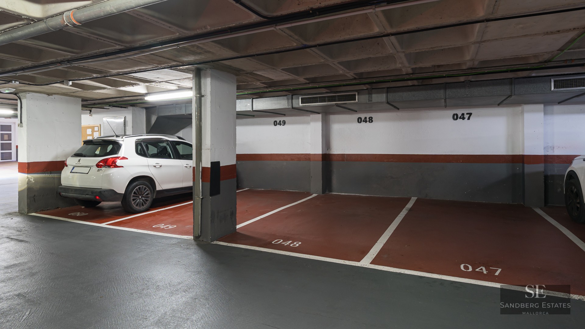 Indoor parking garage with numbered spaces and a white SUV parked next to concrete pillars.